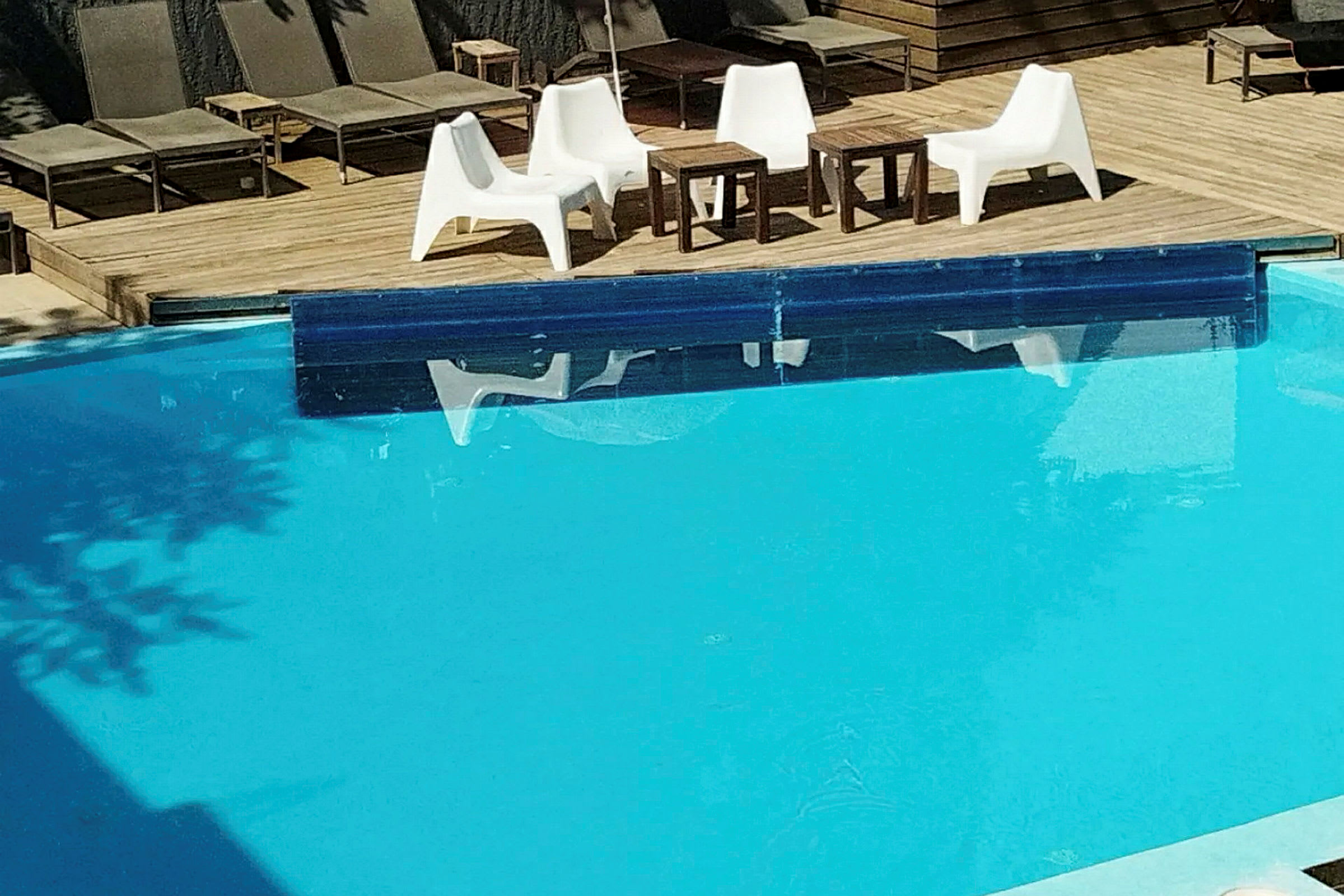 Terrassedekk ved et basseng med flere solsenger og en sittegruppe. (AI-generert tekst)