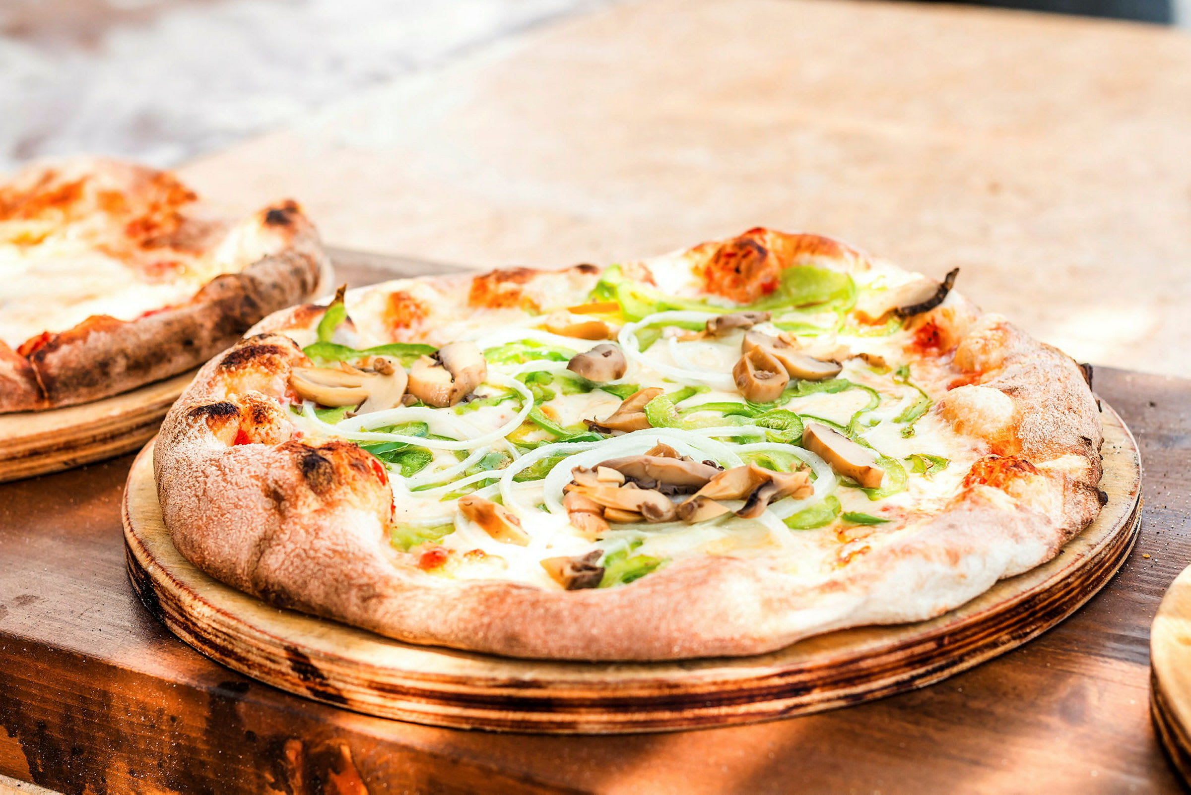 Et nærbilde av en pizza med grønnsaker og sopp, servert på en treplate. (AI-generert tekst)