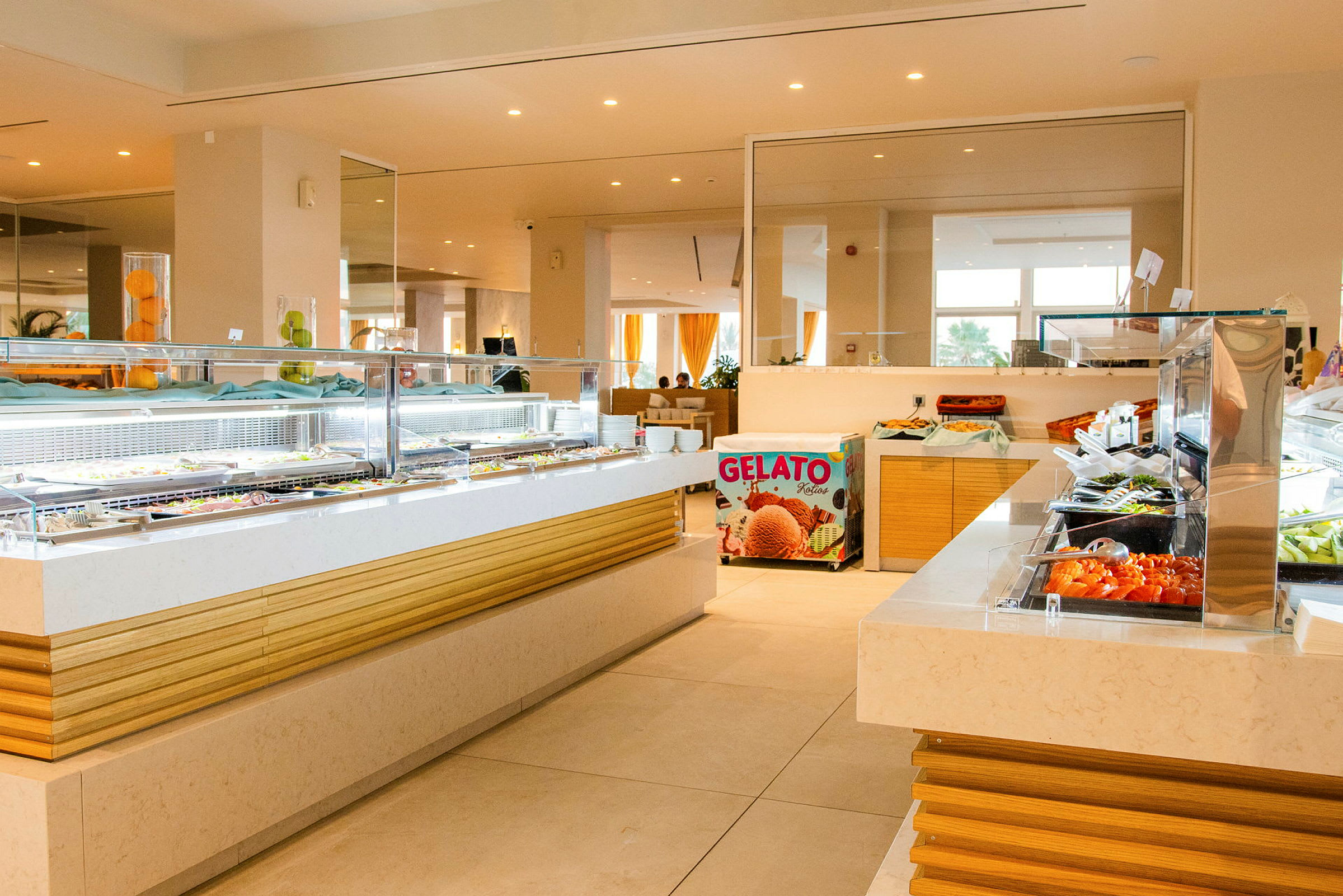Bilde av en hotellbuffet med flere matstasjoner fylt med forskjellige retter og en gelatosalg synlig i bakgrunnen. (AI-generert tekst)
