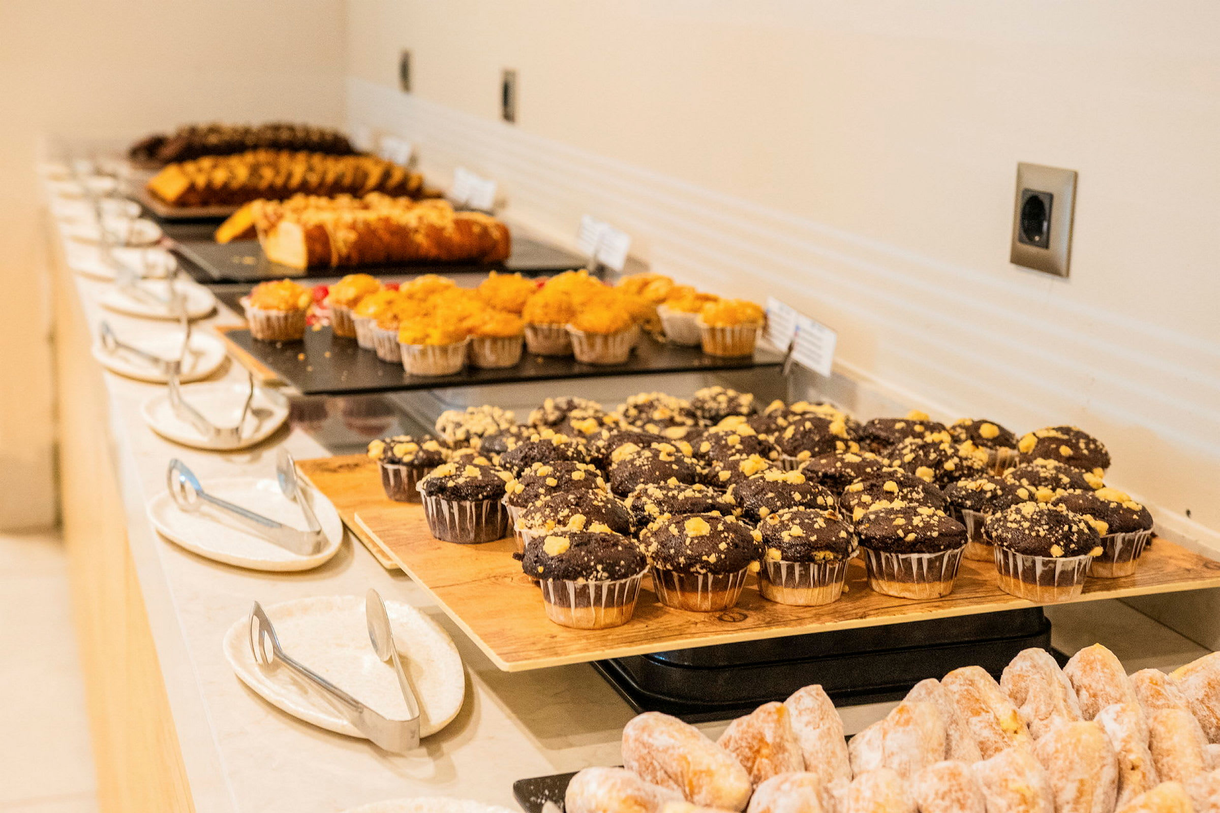 Et bord med ulike typer bakverk, inkludert sjokolademuffins og kaker, arrangert på fat. (AI-generert tekst)