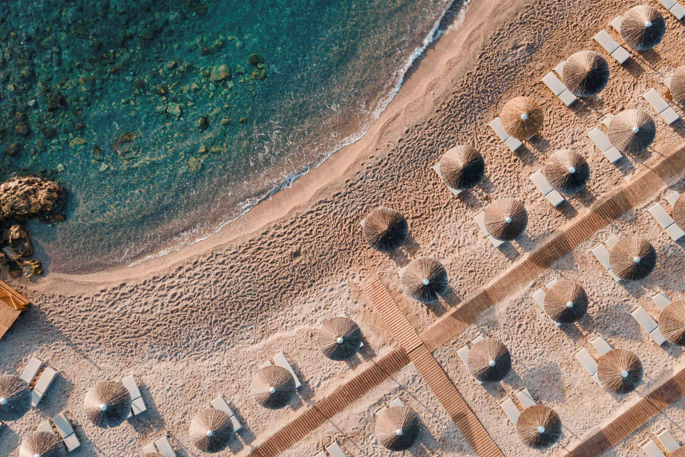 Luftfoto av en sandstrand med parasoller og solsenger. (AI-generert tekst)