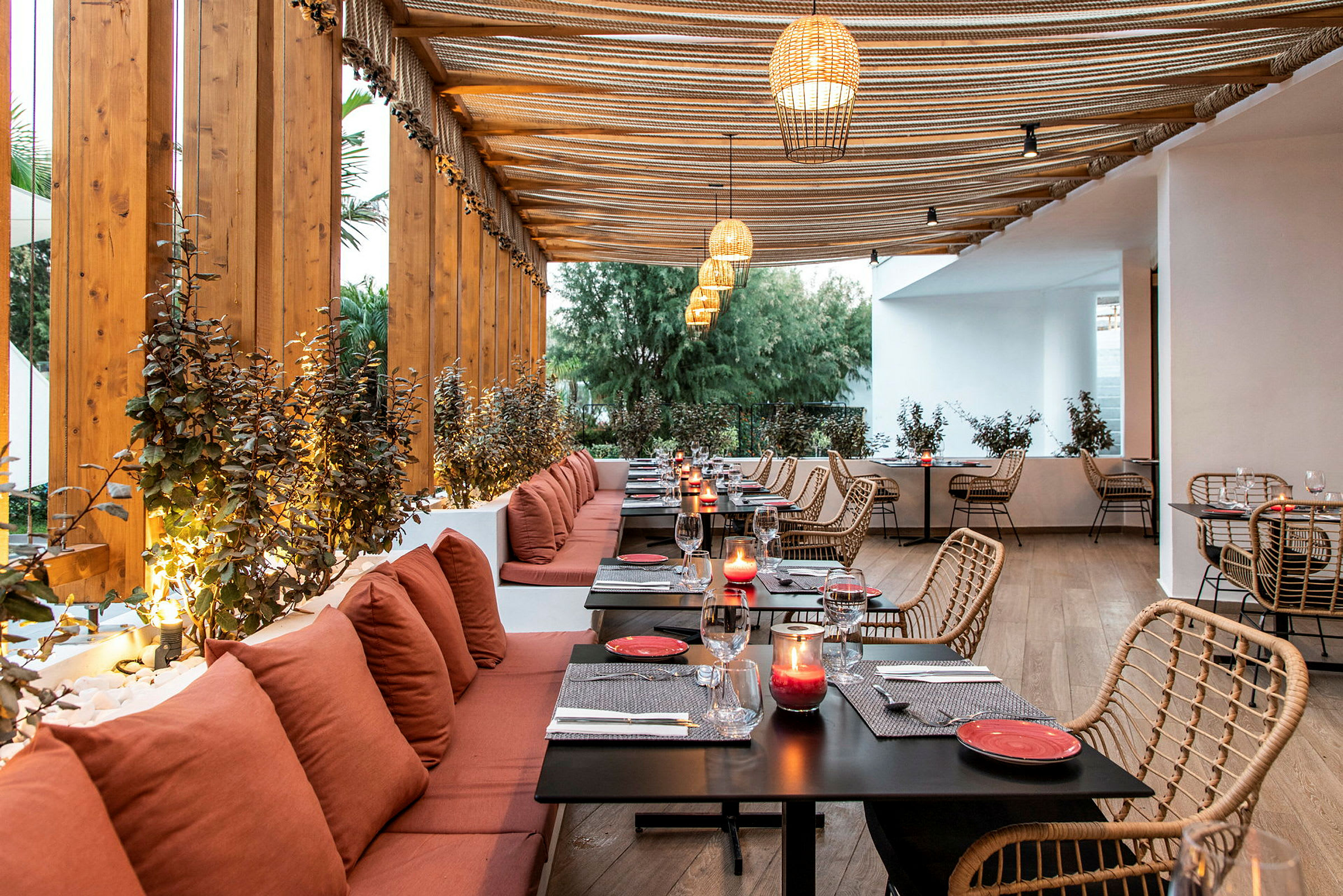 Restaurant med treinnredning, røde puter ved sitteplasser og bord med dekorasjoner. (AI-generert tekst)