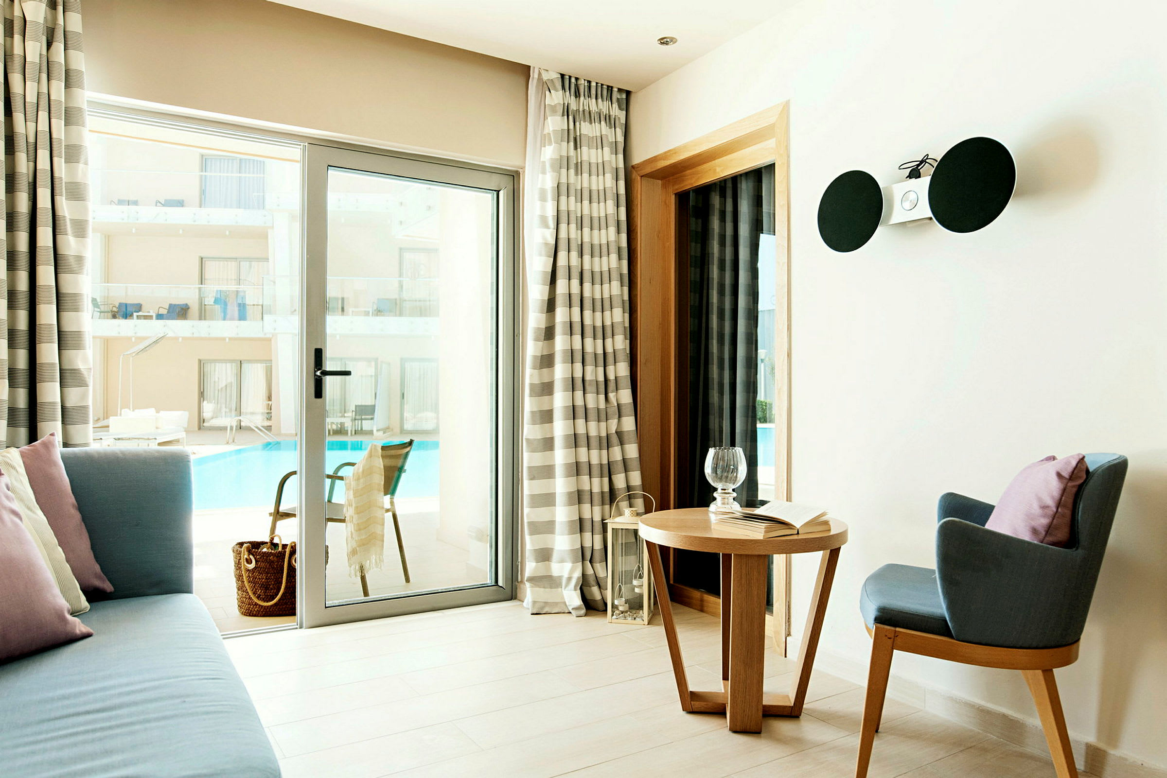 Et hotellrom med sitteområde og utsikt mot bassenget. (AI-generert tekst)