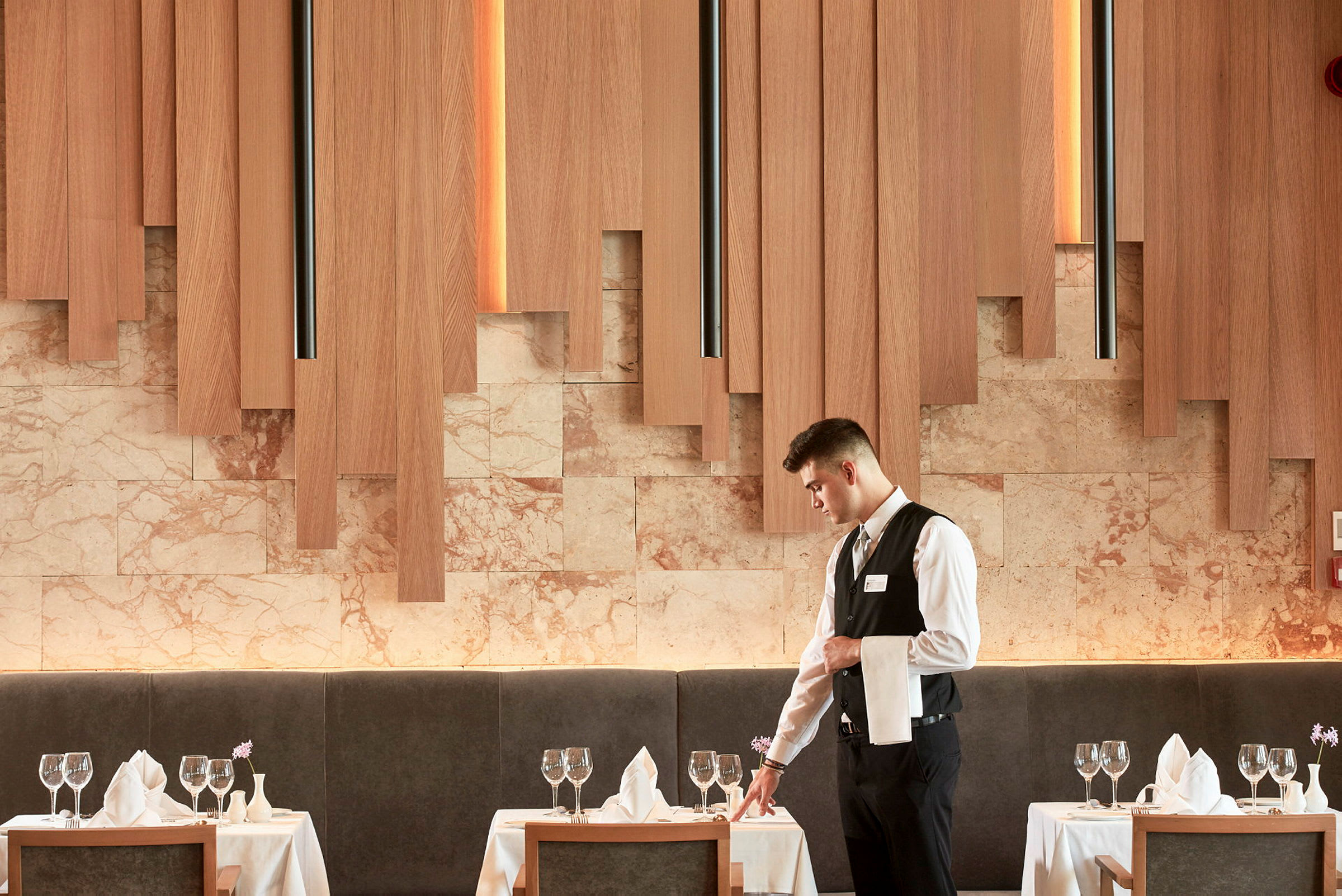 Et elegant restaurantmiljø med dekkede bord, glass og servietter, og trepaneler på veggene. (AI-generert tekst)