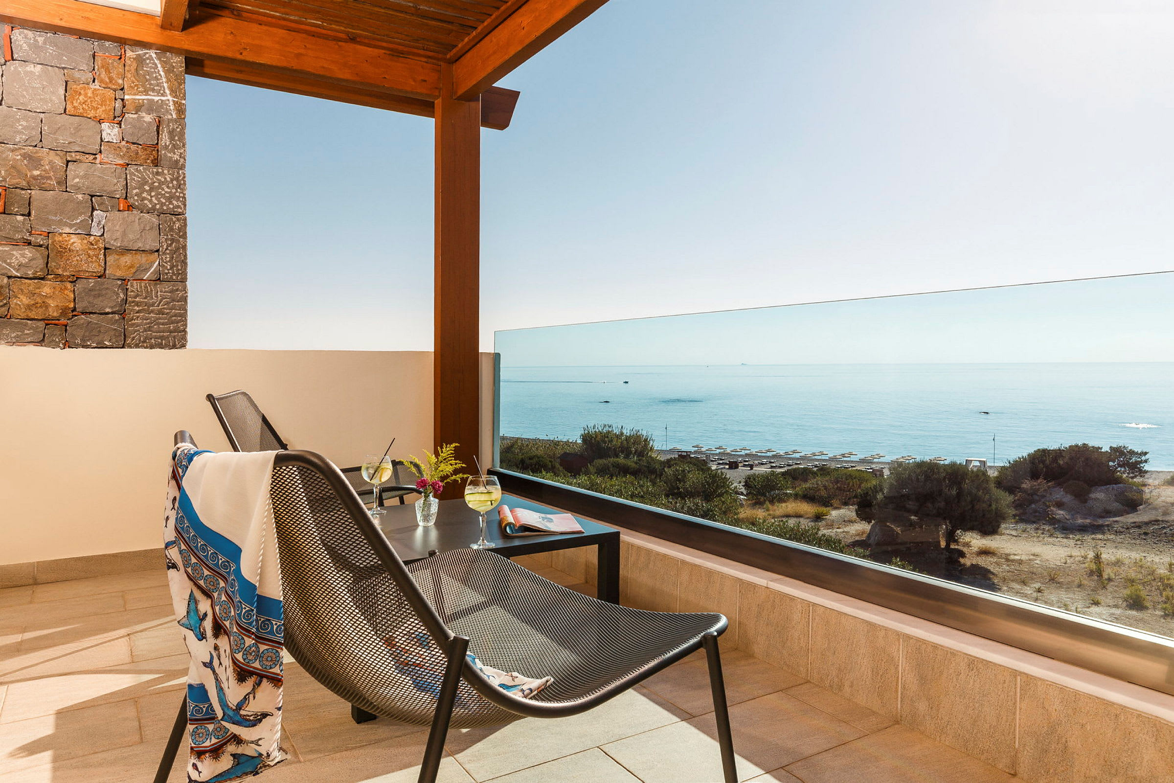 Terrasse med utsikt over havet, møbler og drikke på bordet. (AI-generert tekst)