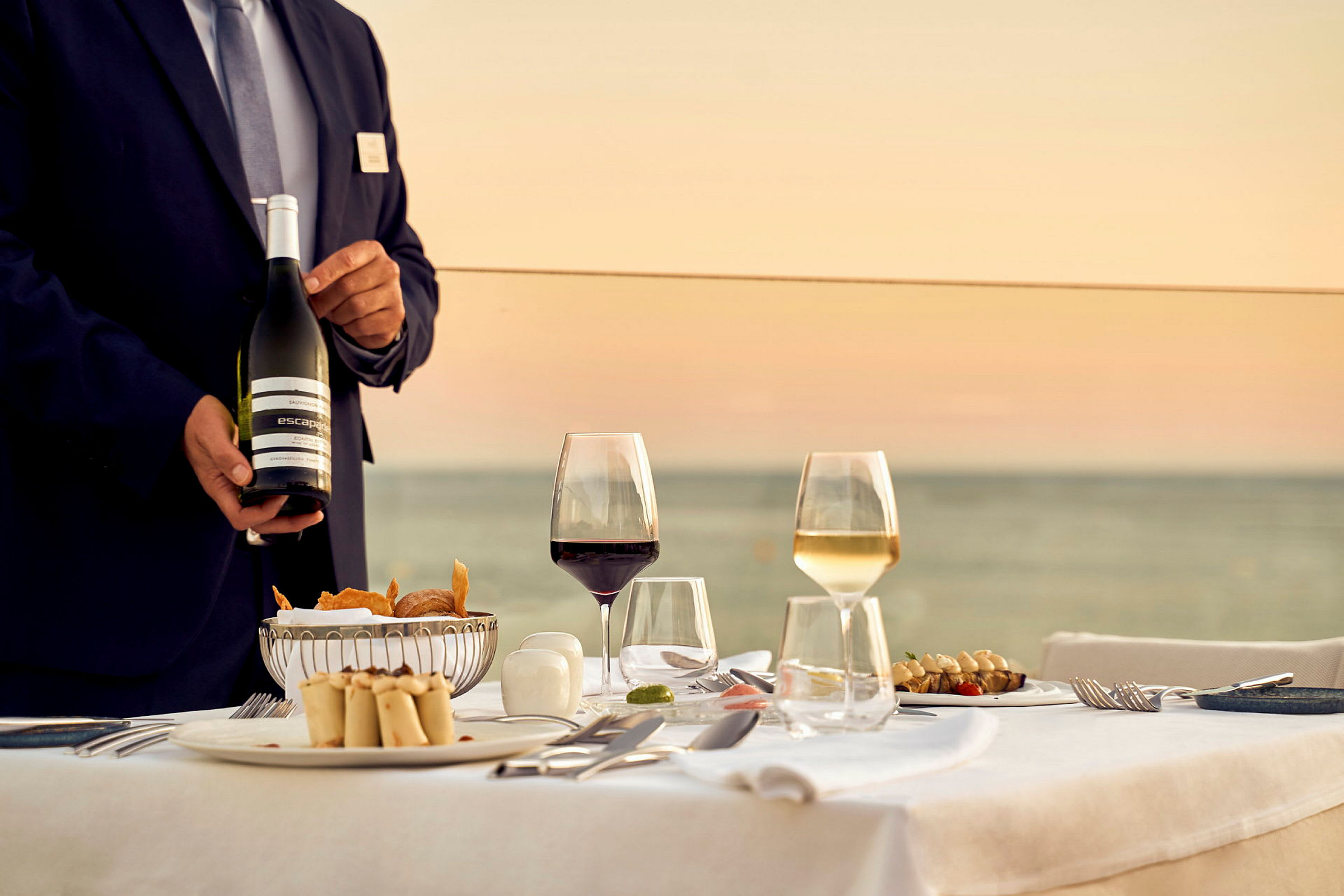 Restaurantbord med servering av mat og drikke ved solnedgang. (AI-generert tekst)