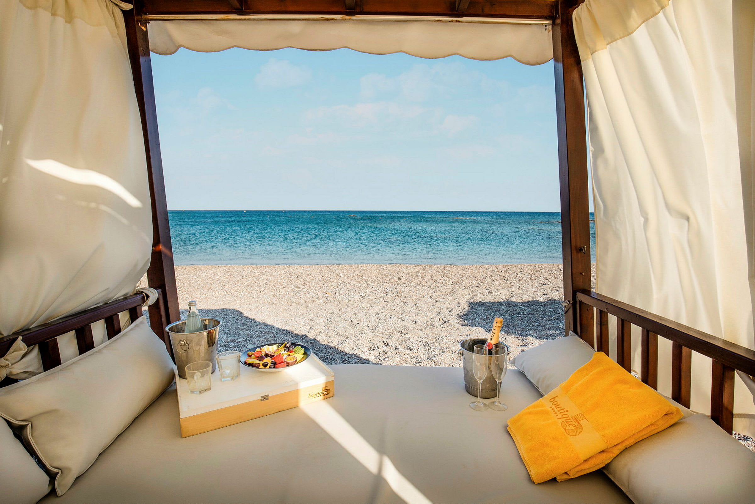 Utsikt fra en solseng mot en strand med blått hav i bakgrunnen. (AI-generert tekst)