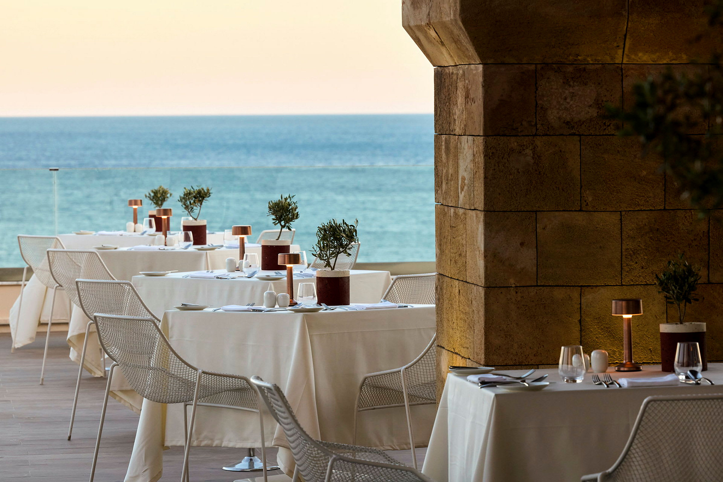 En utendørs restaurant med dekkede bord og utsikt over havet. (AI-generert tekst)