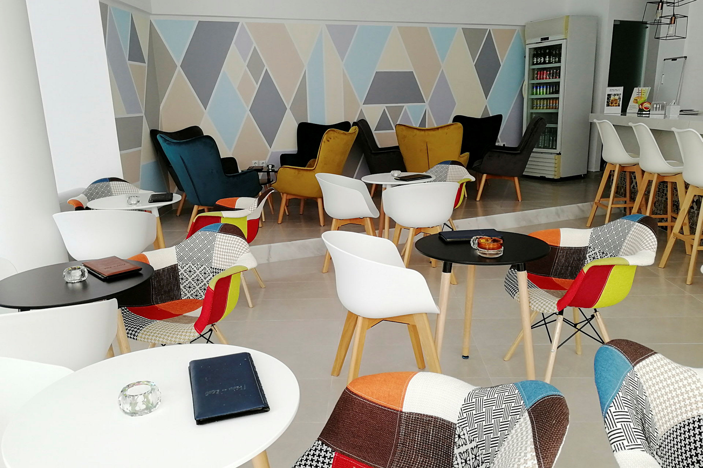 En moderne lounge med fargerike stoler og geometriske mønstre på veggen. (AI-generert tekst)