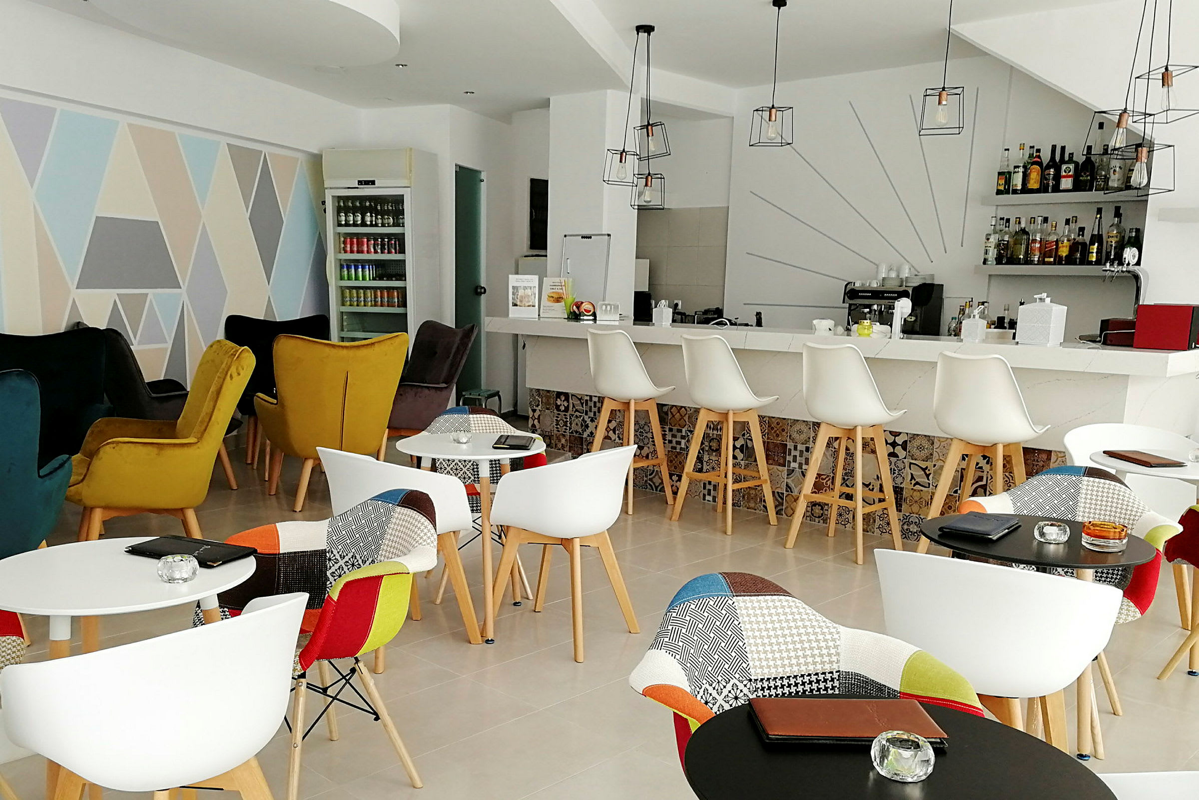 Innendørs bilde av en elegant kafé med fargerike stoler, et barområde og dekorative elementer. (AI-generert tekst)