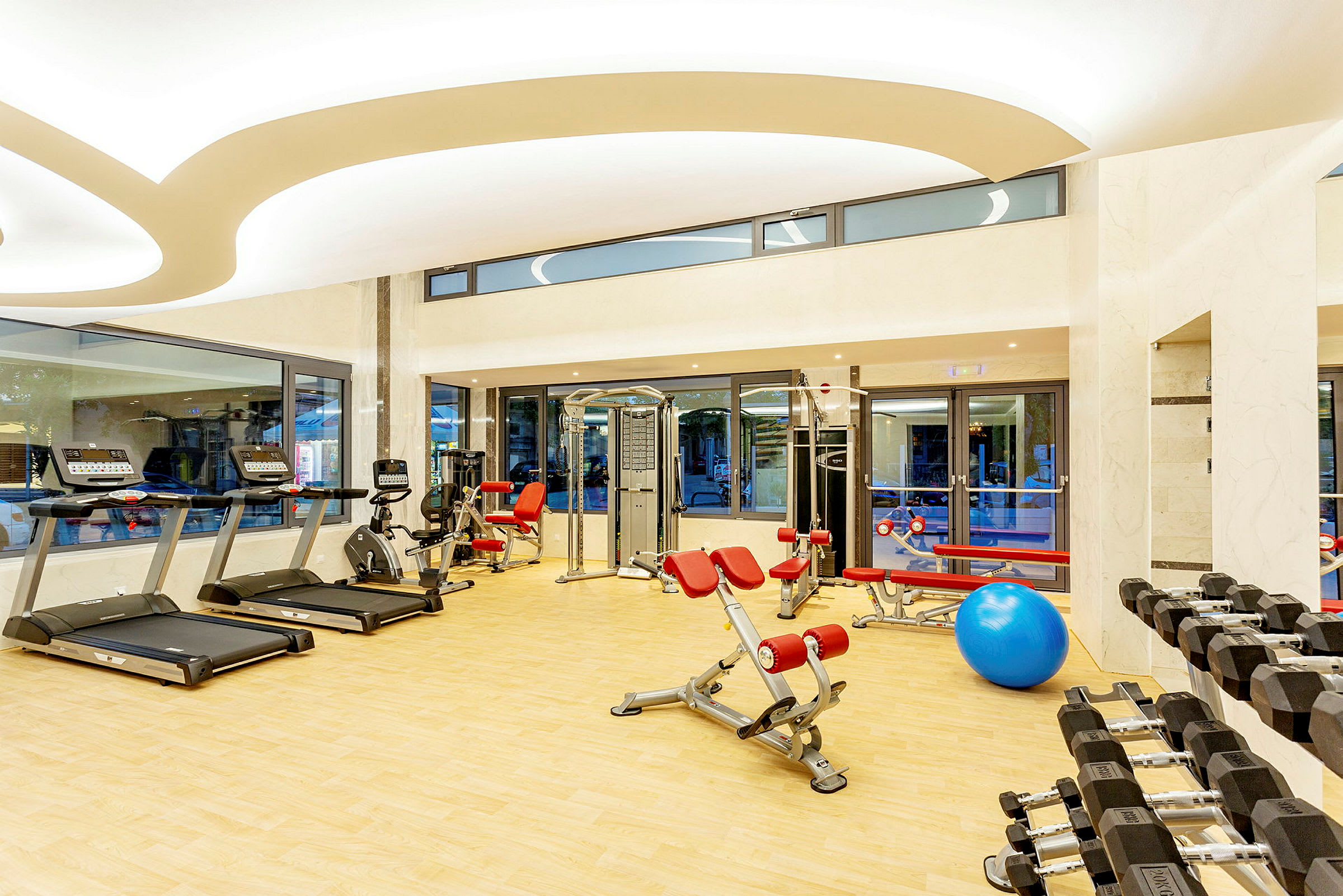Et treningsrom med treningsmaskiner, frie vekter og en stor blå pilatesball. (AI-generert tekst)