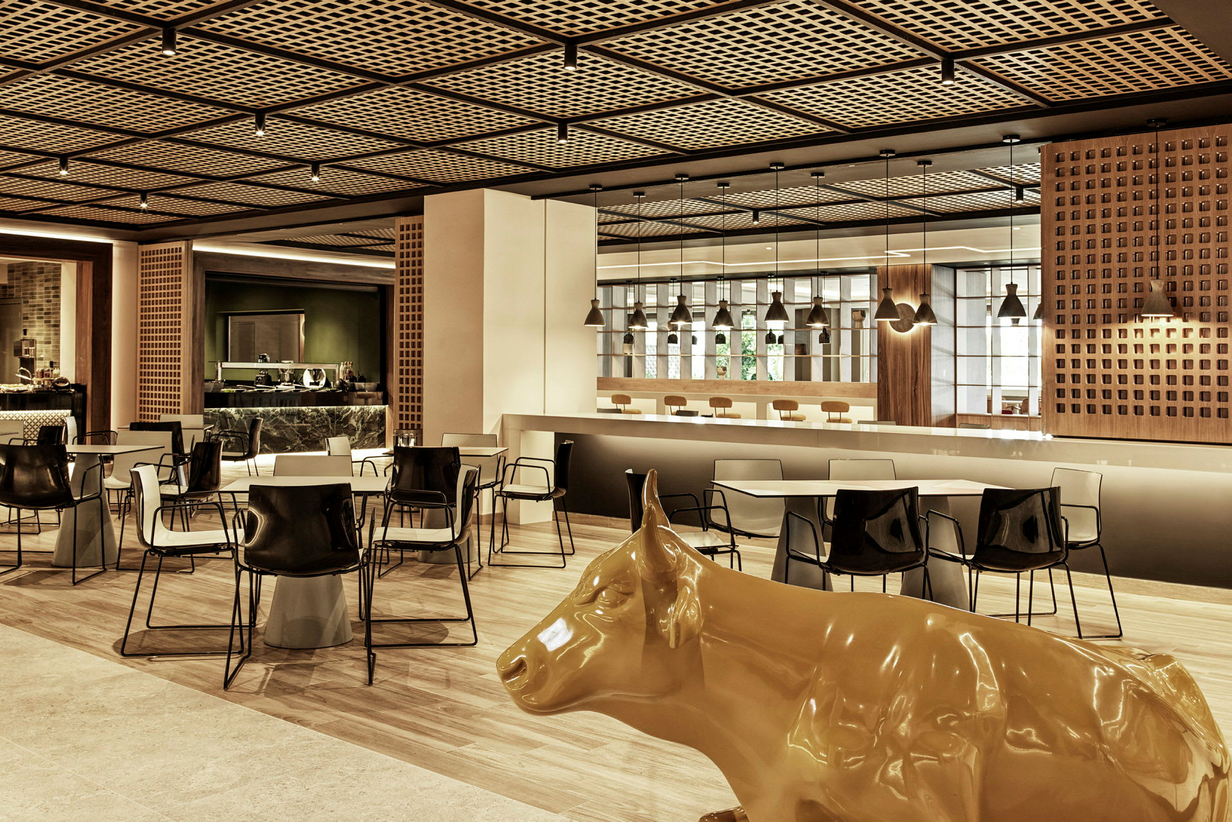 En moderne restaurant med bord, stoler og en gul statue av en ku. (AI-generert tekst)