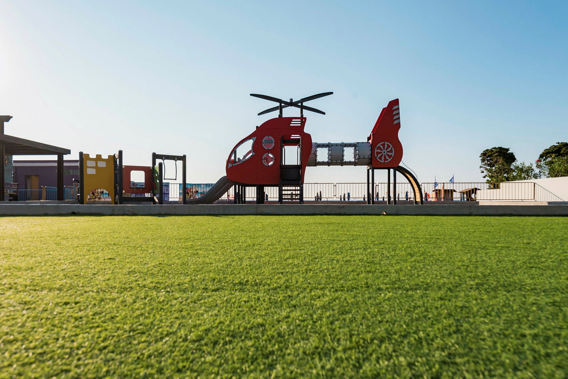 Lekeplass med helikopterformede lekestrukturer og grønnsområde. (AI-generert tekst)