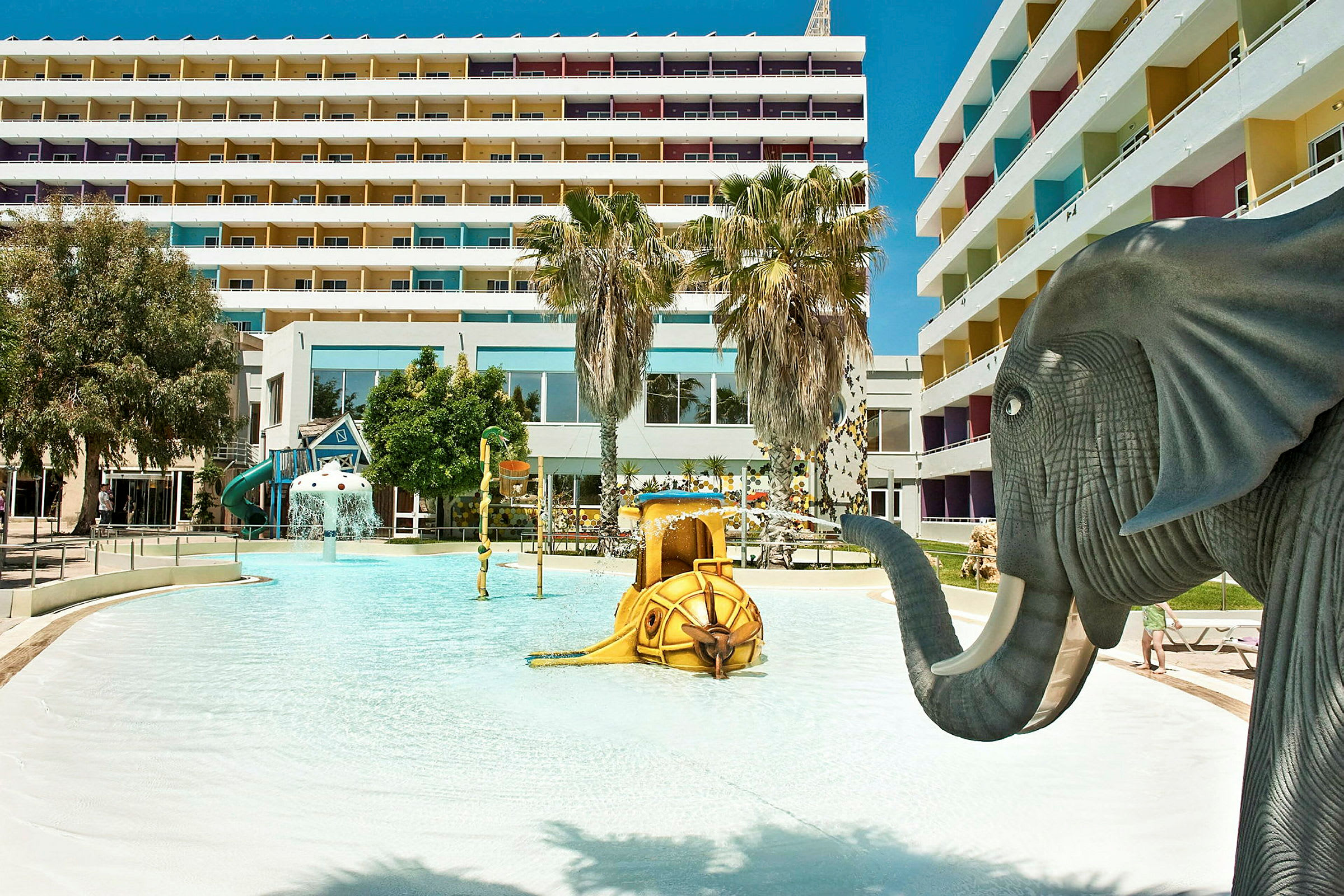 Barnebasseng med elefantfigur og lekeskulpturer ved hotellkompleks. (AI-generert tekst)