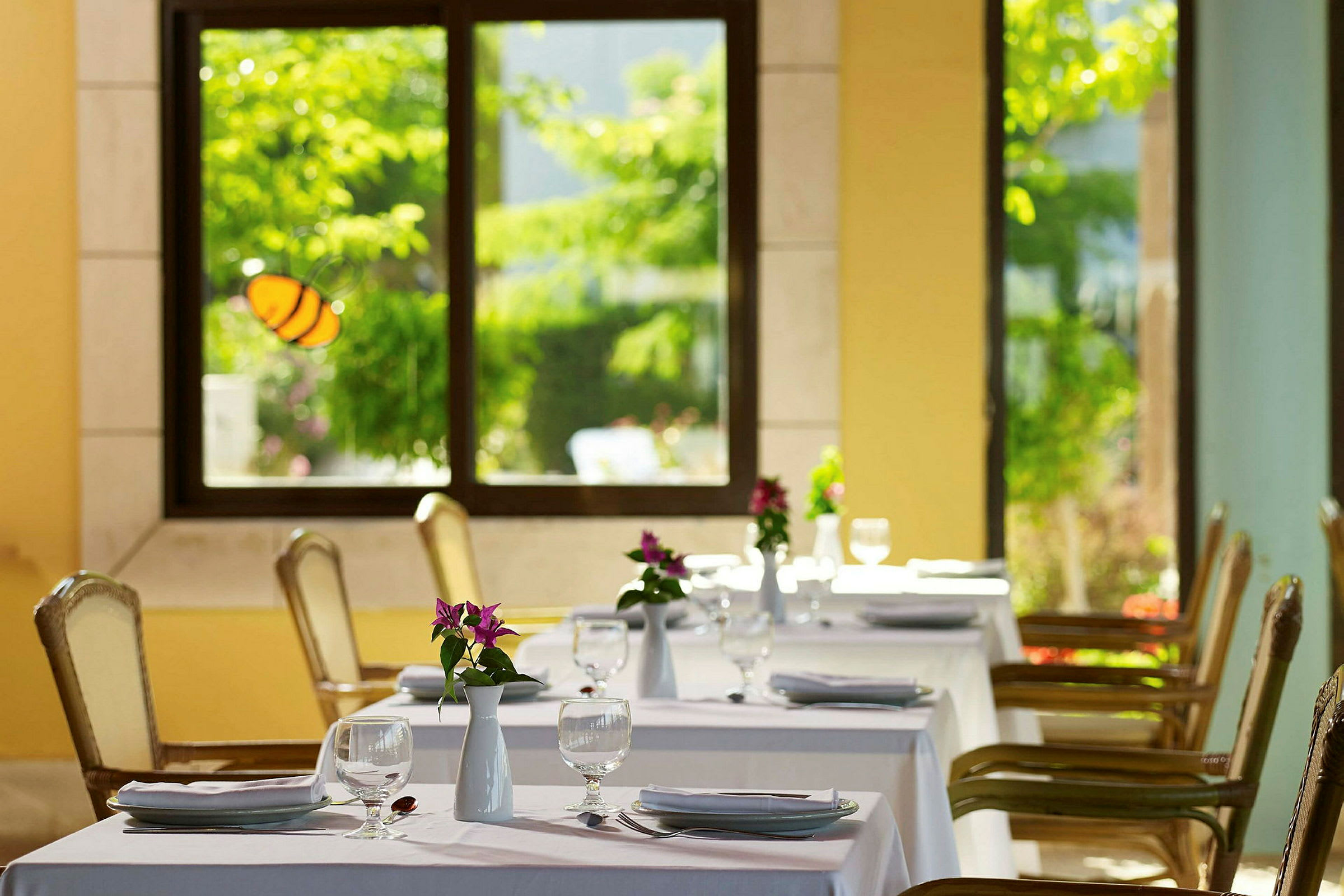 Restaurant med dekkede bord og blomster i et lyst miljø. (AI-generert tekst)