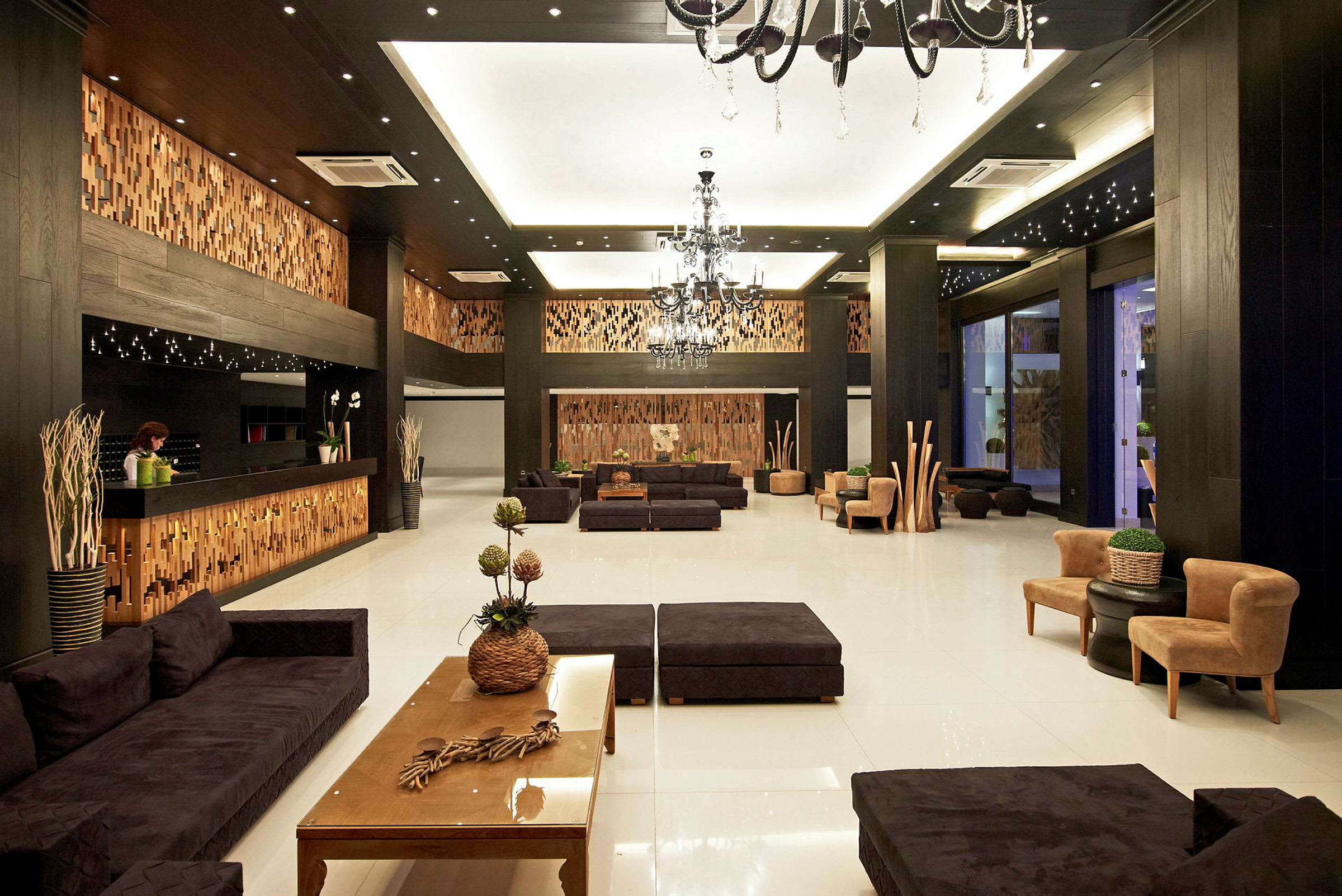 En hotellobby med moderne innredning, inkludert sofaer, bord og dekorative planter. (AI-generert tekst)