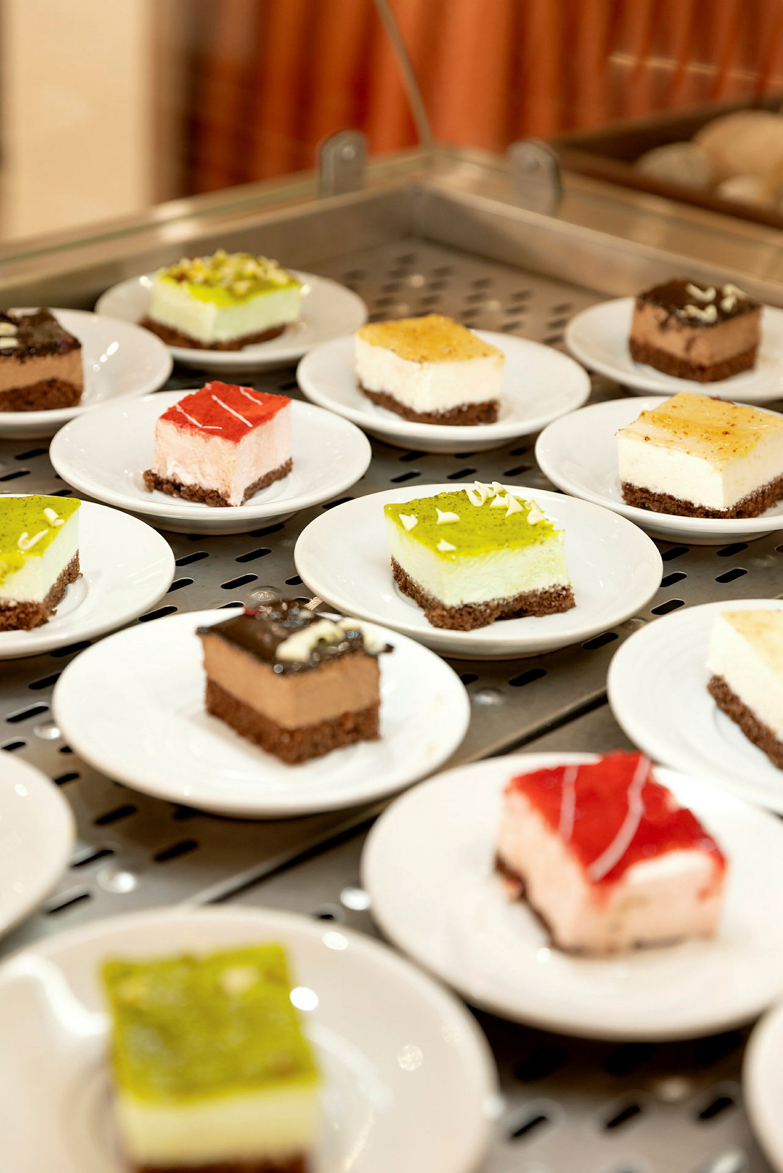 Flere små desserter på hvite tallerkener, presentert på en serveringsflate. (AI-generert tekst)