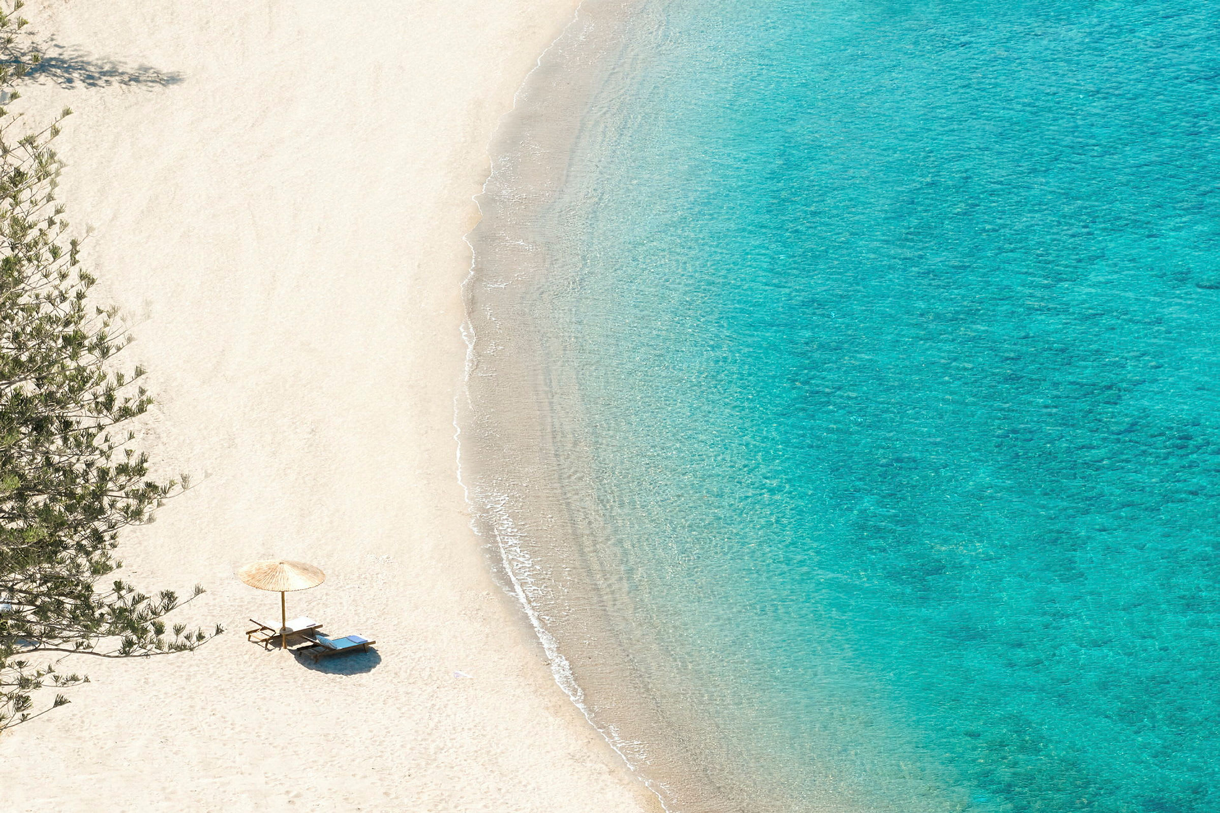 Strand med parasoll og solsenger ved vannkanten. (AI-generert tekst)
