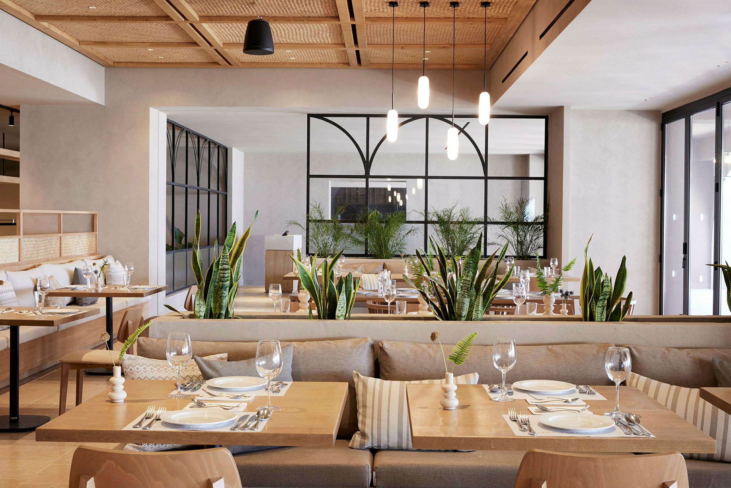 Bilde av en restaurant med moderne innredede spisebord og grønne planter. (AI-generert tekst)