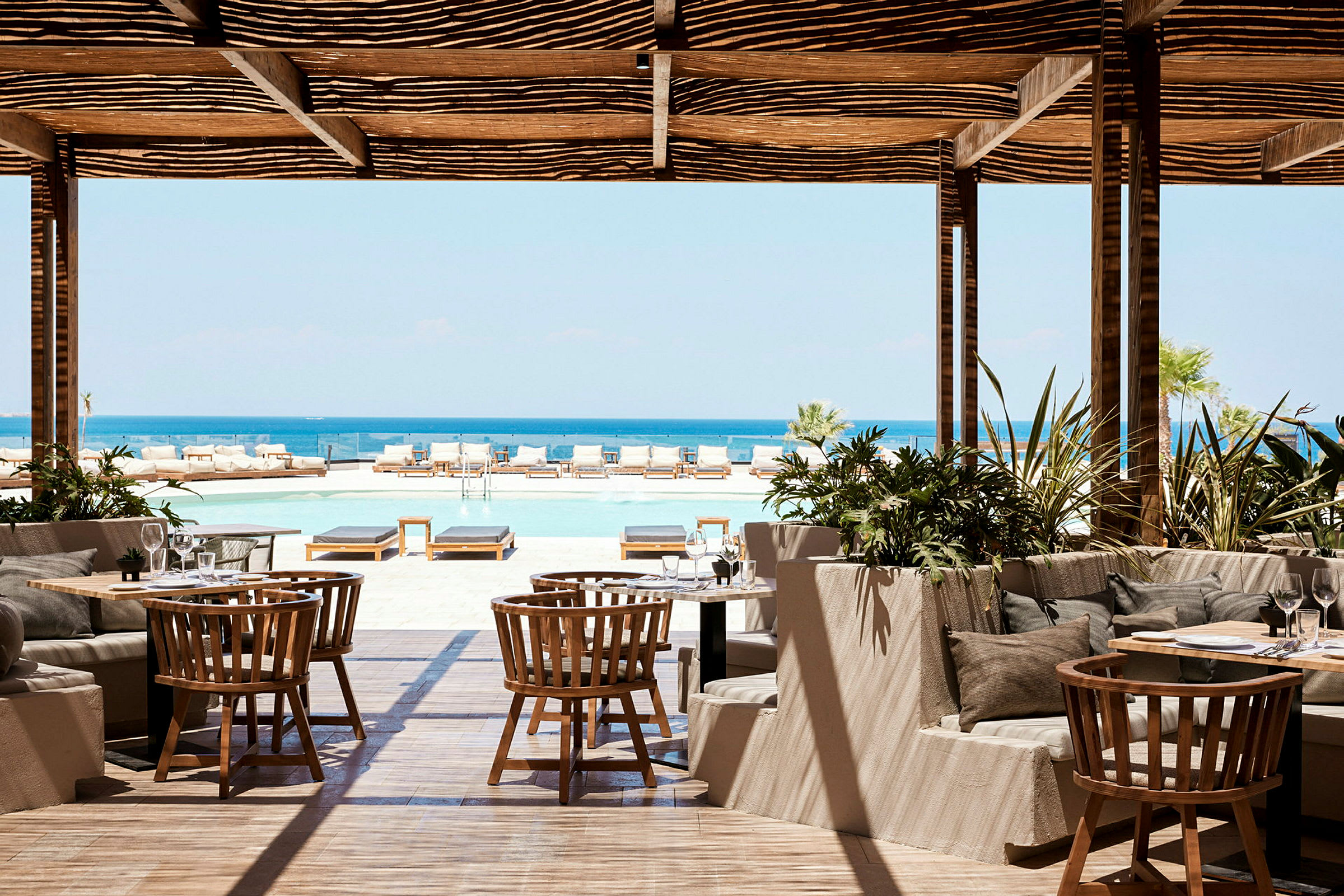Restaurant med utsikt over et basseng og havet. (AI-generert tekst)