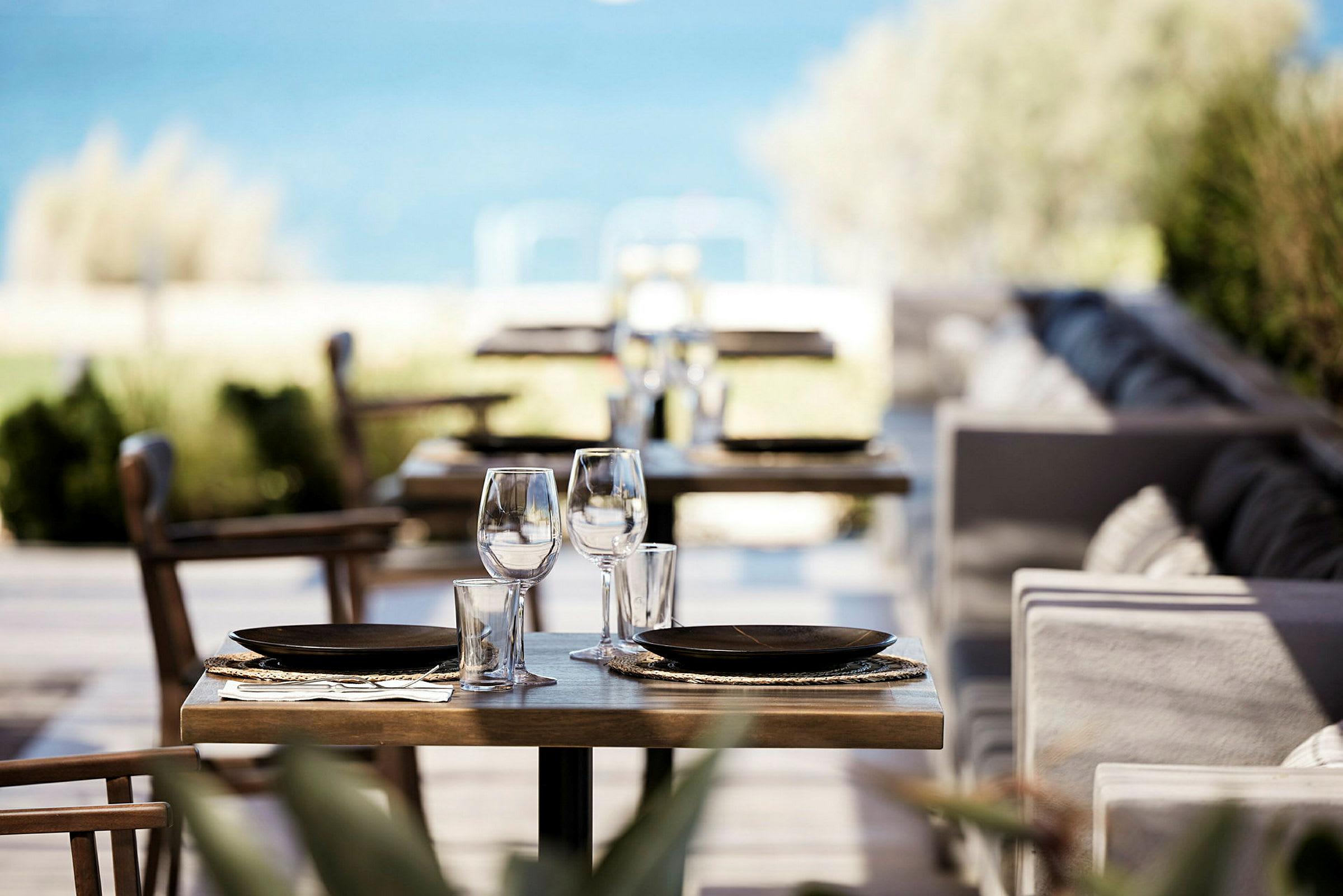 Bilde av et dekket bord på en restaurant med havet i bakgrunnen. (AI-generert tekst)