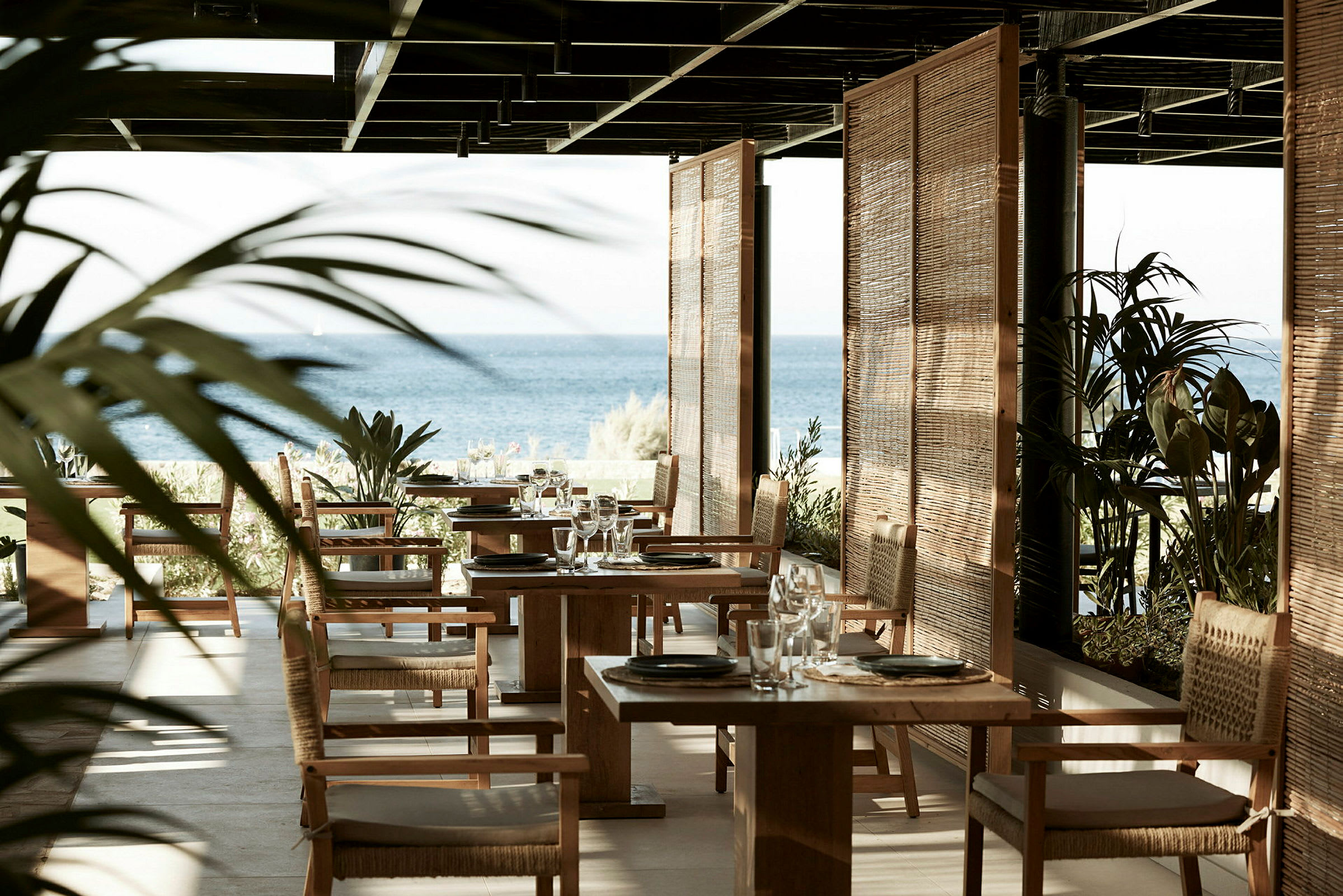 Restaurant med havutsikt, trestoler og bord. (AI-generert tekst)