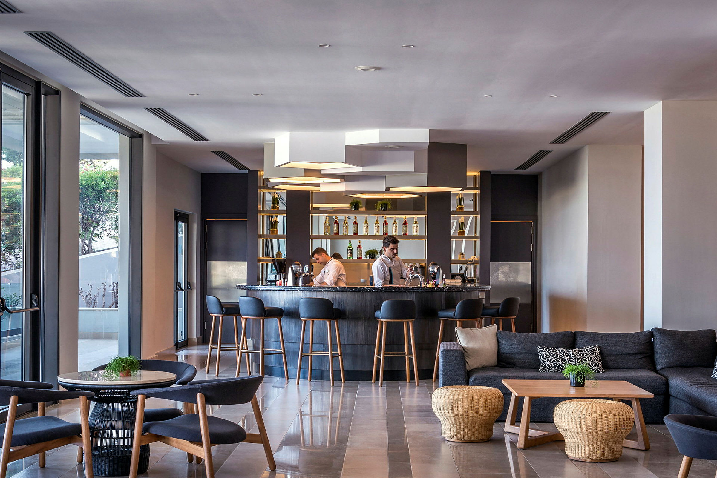 Hotellbar med stoler og sofaer, samt personale bak disken. (AI-generert tekst)