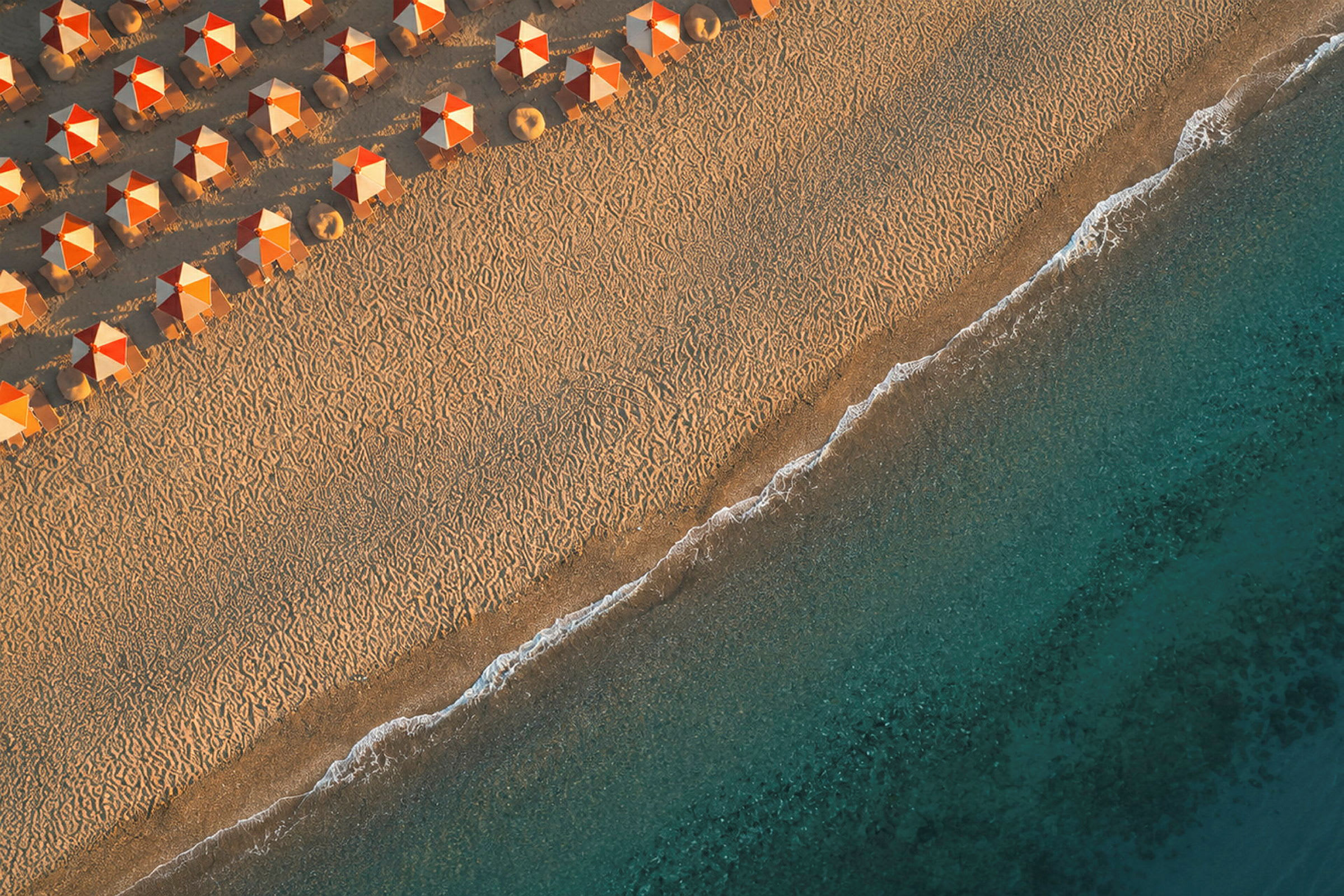 Strand med oransje parasoller og blått hav. (AI-generert tekst)