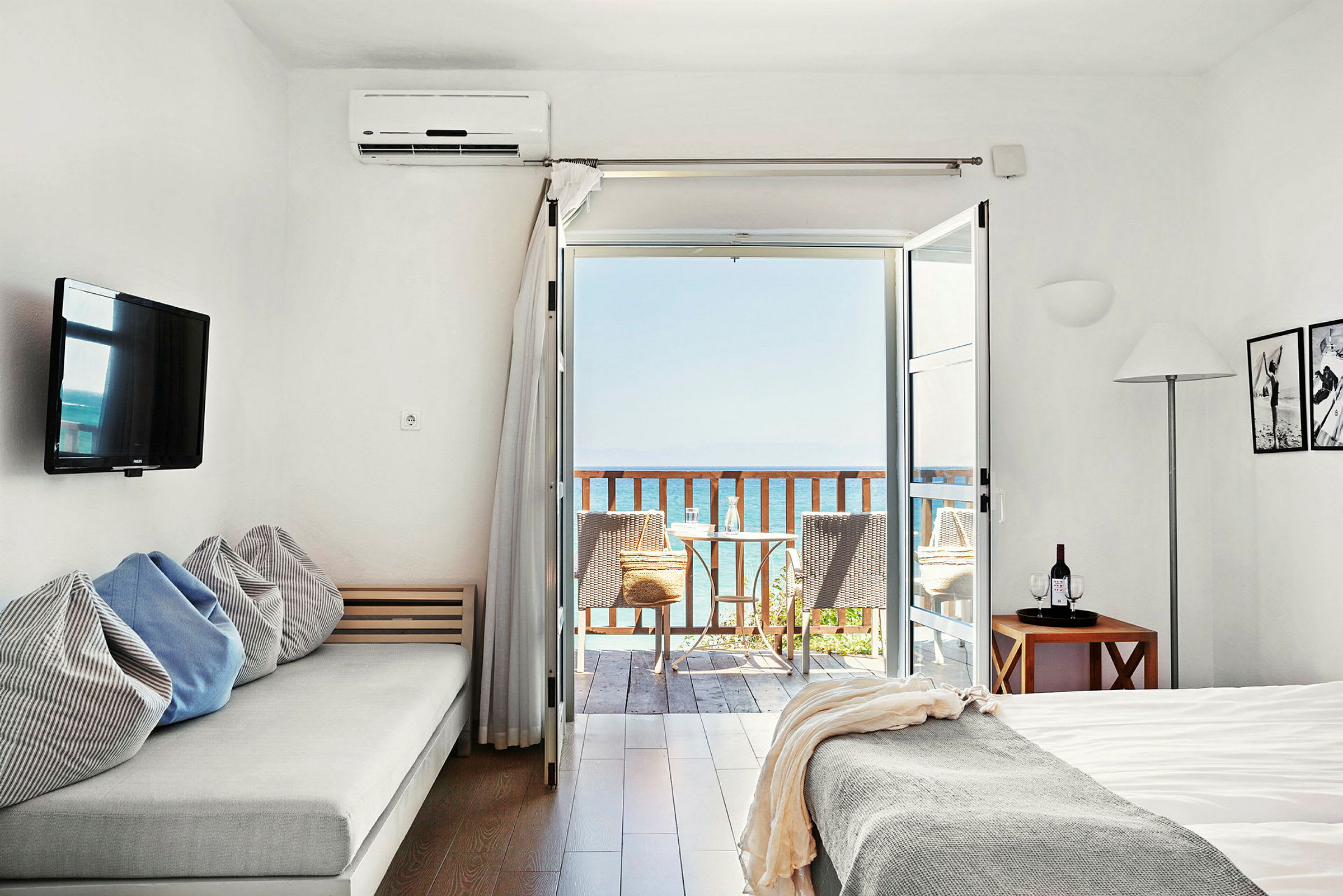 Et lyst hotellrom med havutsikt fra en balkong. (AI-generert tekst)