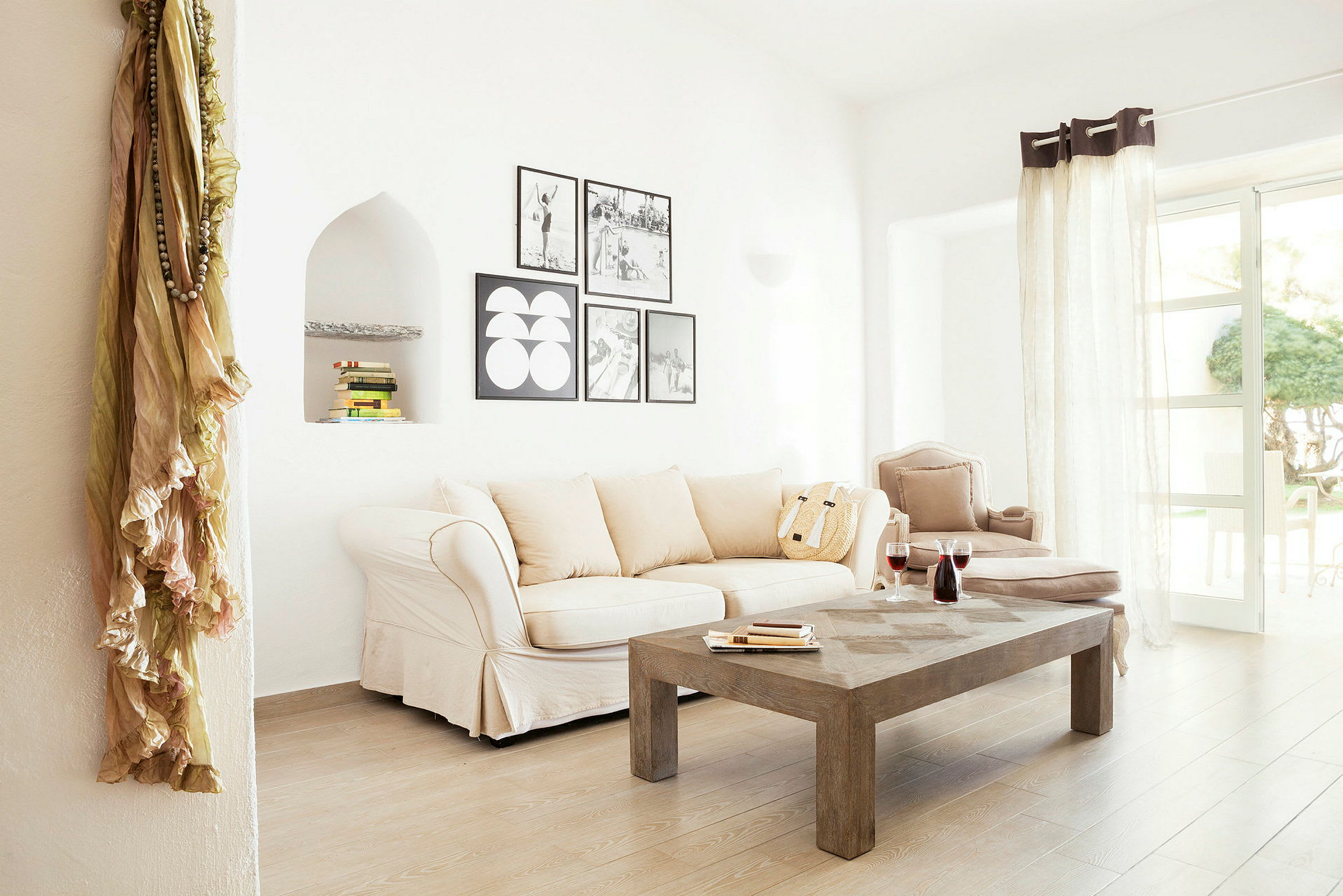 Et lyst stue med beige sofa, trebord og dekorative veggbilder. (AI-generert tekst)