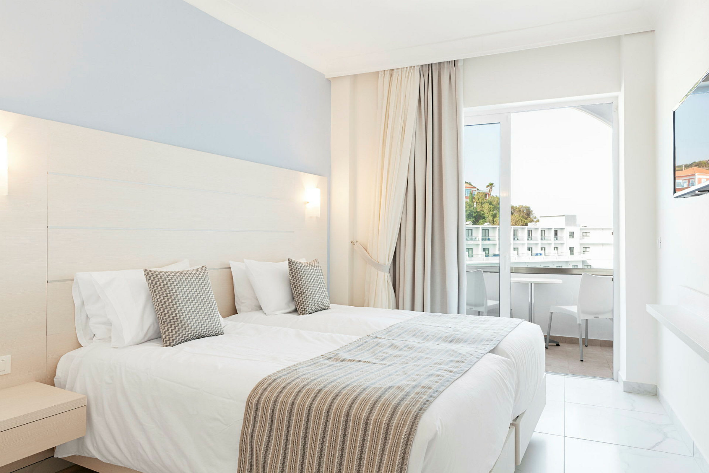 Hotellrom med to enkeltsenger og balkong. (AI-generert tekst)