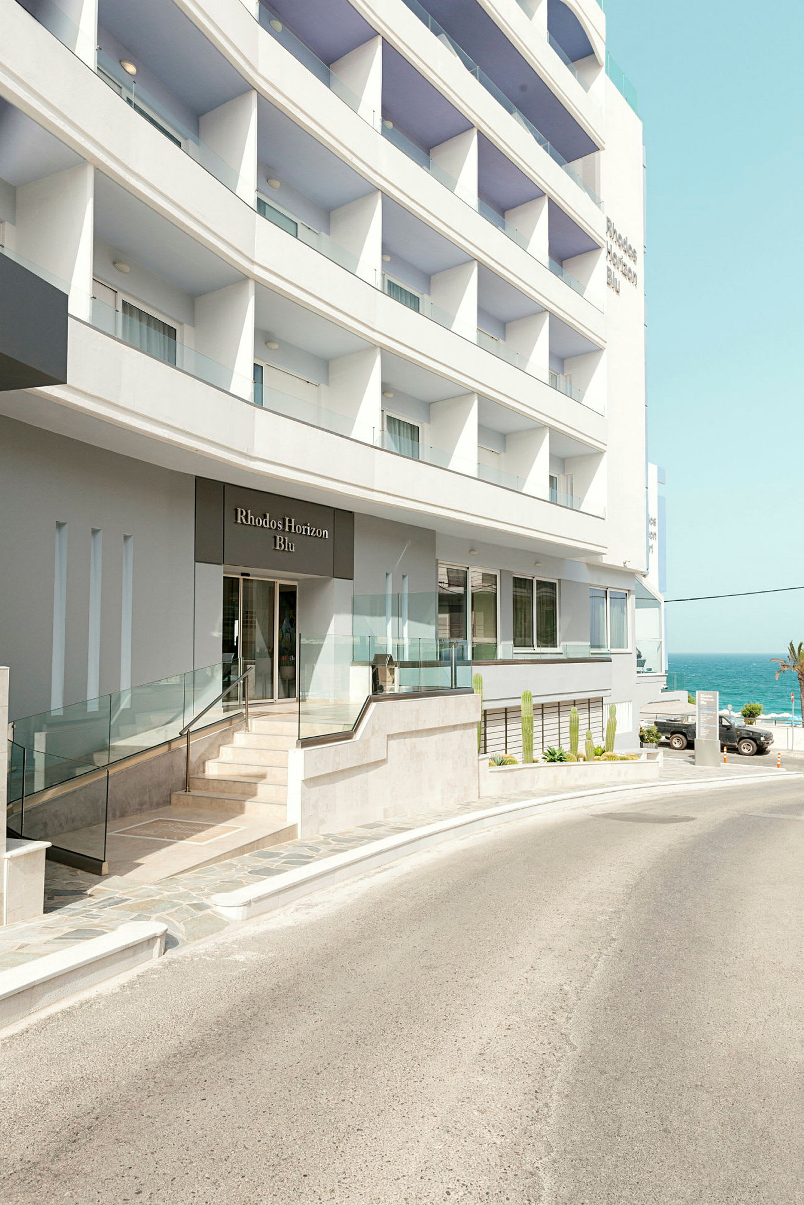 Hotellbygning med inngang og utsikt mot havet. (AI-generert tekst)