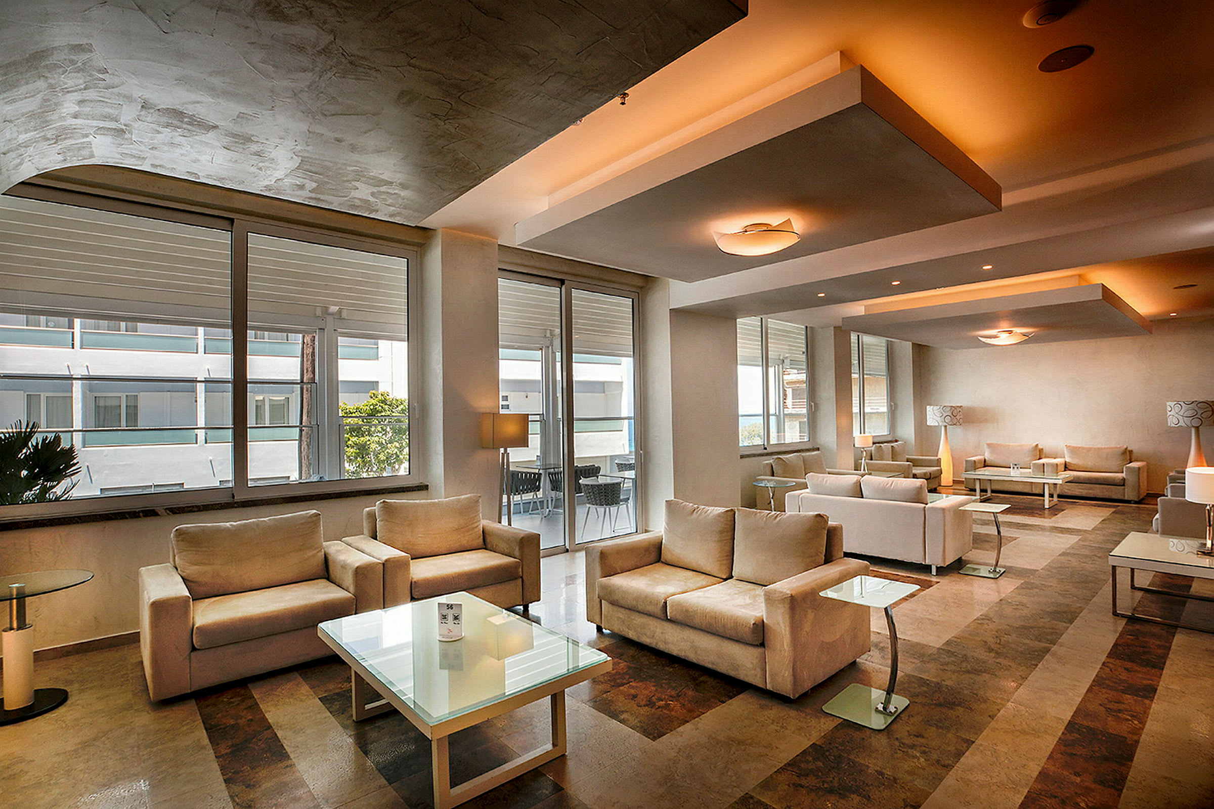 Moderne innredet hotellfoajé med beige sofaer og glassbord. (AI-generert tekst)