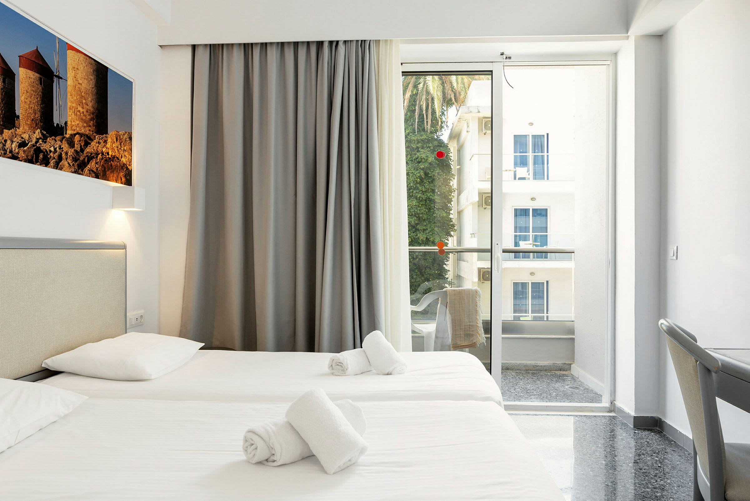 Hotellrom med to enkeltsenger, balkong med utsikt. (AI-generert tekst)