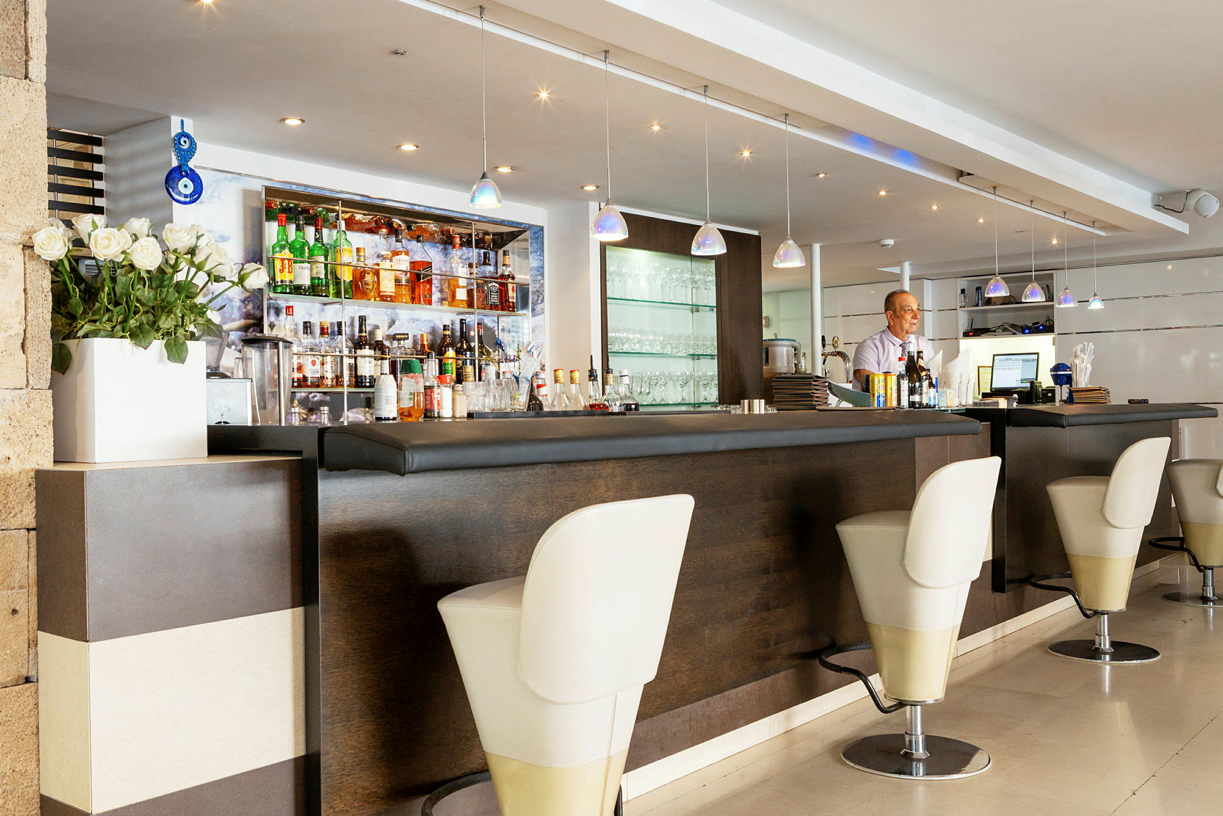 En hotellbar med elegant interiør inkludert en sitteavdeling med høye stoler og flasker samt glass på en hylle. (AI-generert tekst)