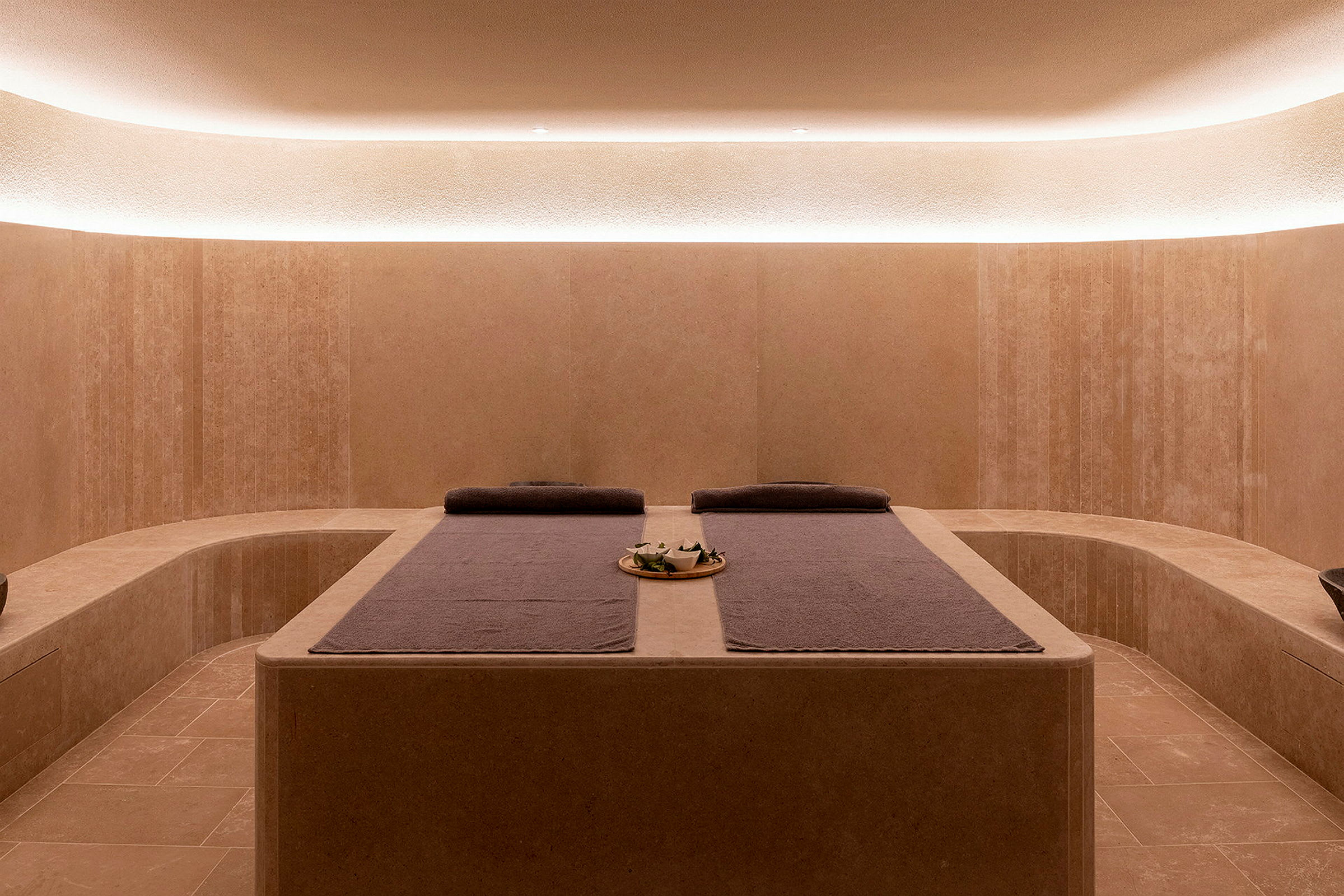 Et moderne spa-rom med avslappende belysning og to massasjebenker med håndklær. (AI-generert tekst)