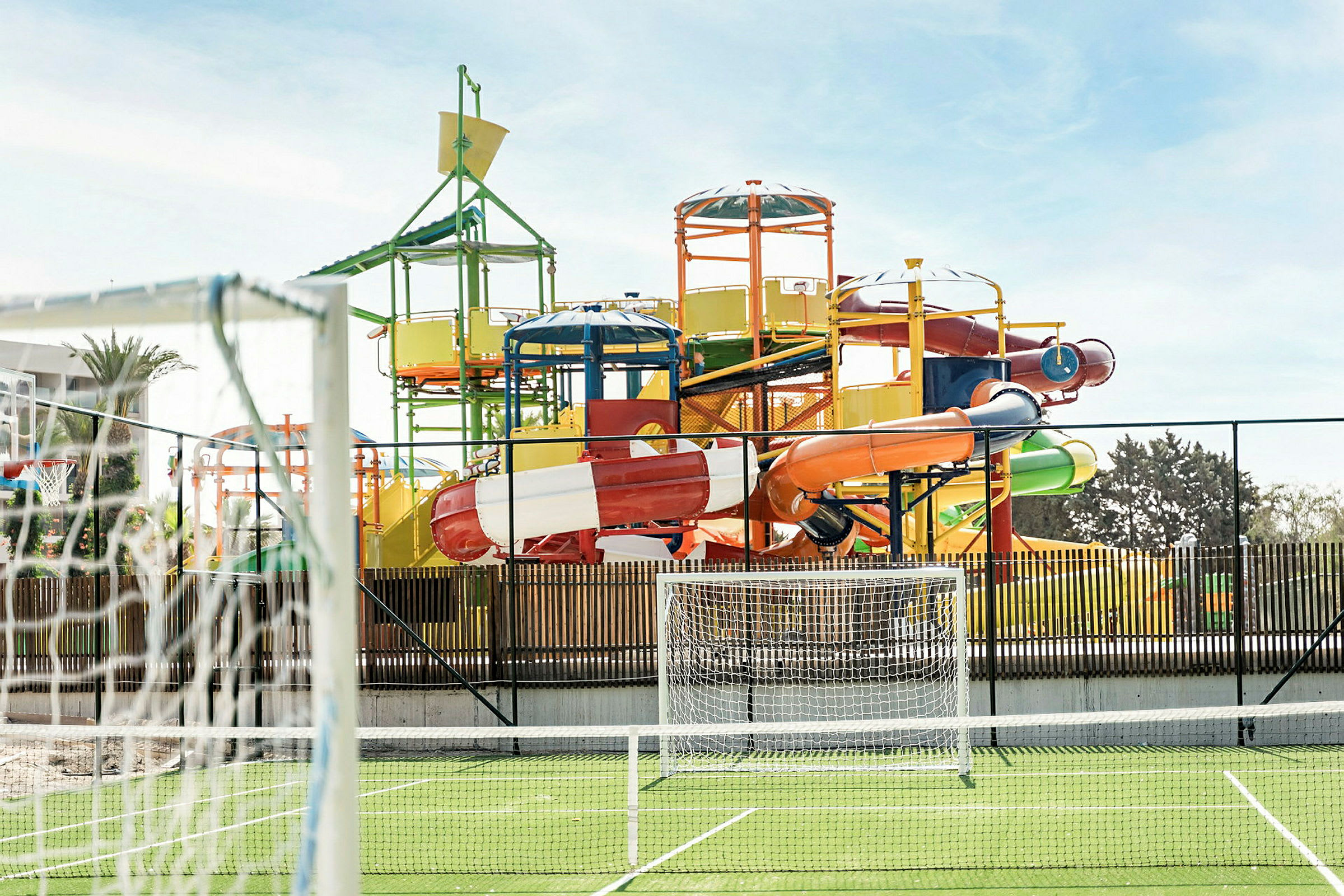 En fargerik vannpark med flere vannsklier og et fotballmål i forgrunnen. (AI-generert tekst)
