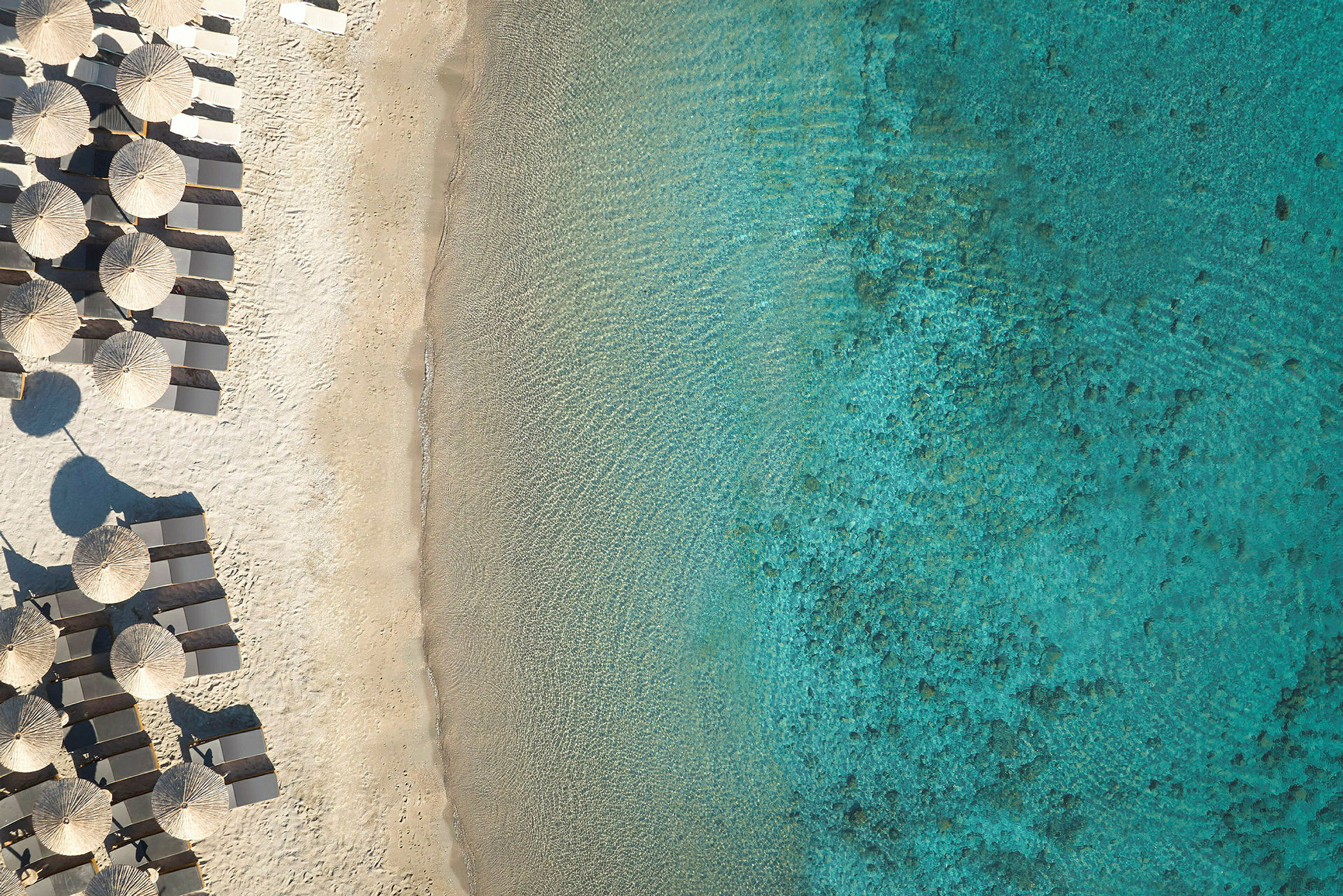 Strand med solsenger og parasoller ved siden av turkis hav. (AI-generert tekst)
