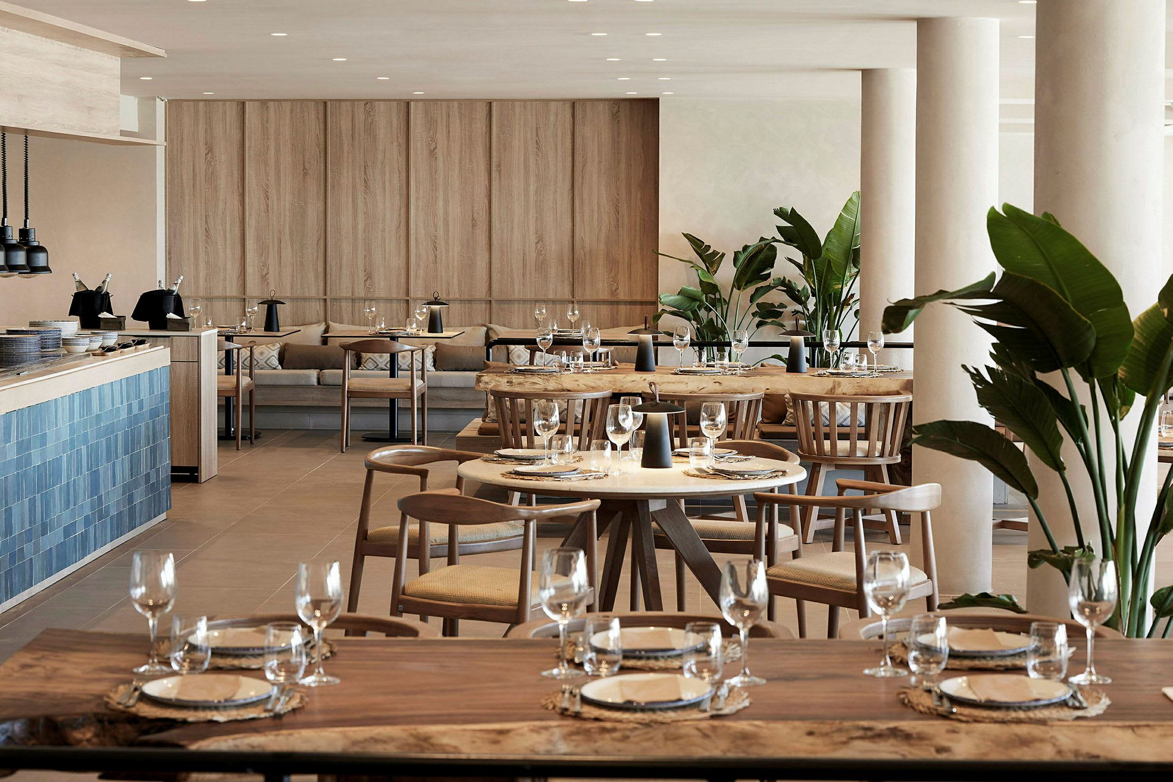 En moderne restaurant med trebord, stoler og dekorativ grønne planter. (AI-generert tekst)