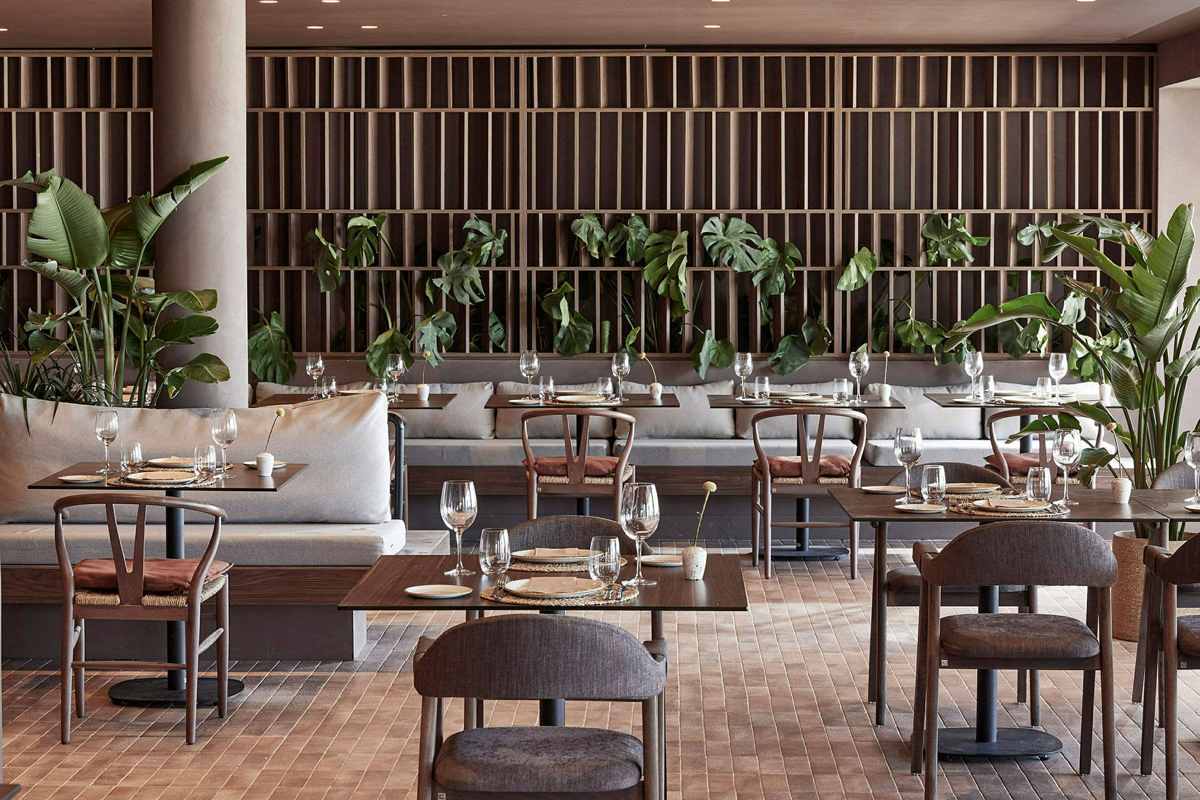 Restaurant med dekkede bord, moderne møbler og grønne planter. (AI-generert tekst)
