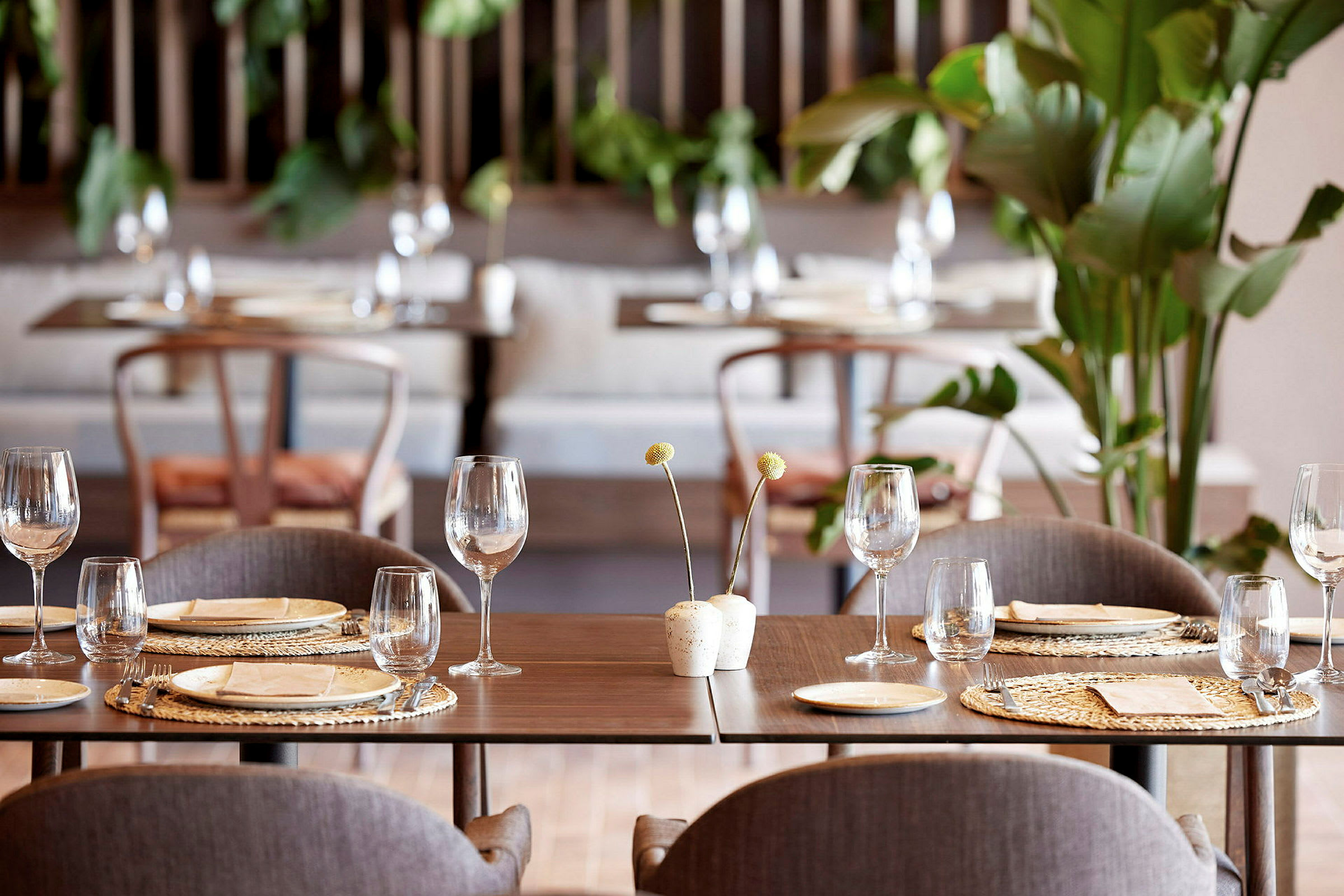 Interiør av en moderne restaurant med dekkede bord, glass og planter. (AI-generert tekst)