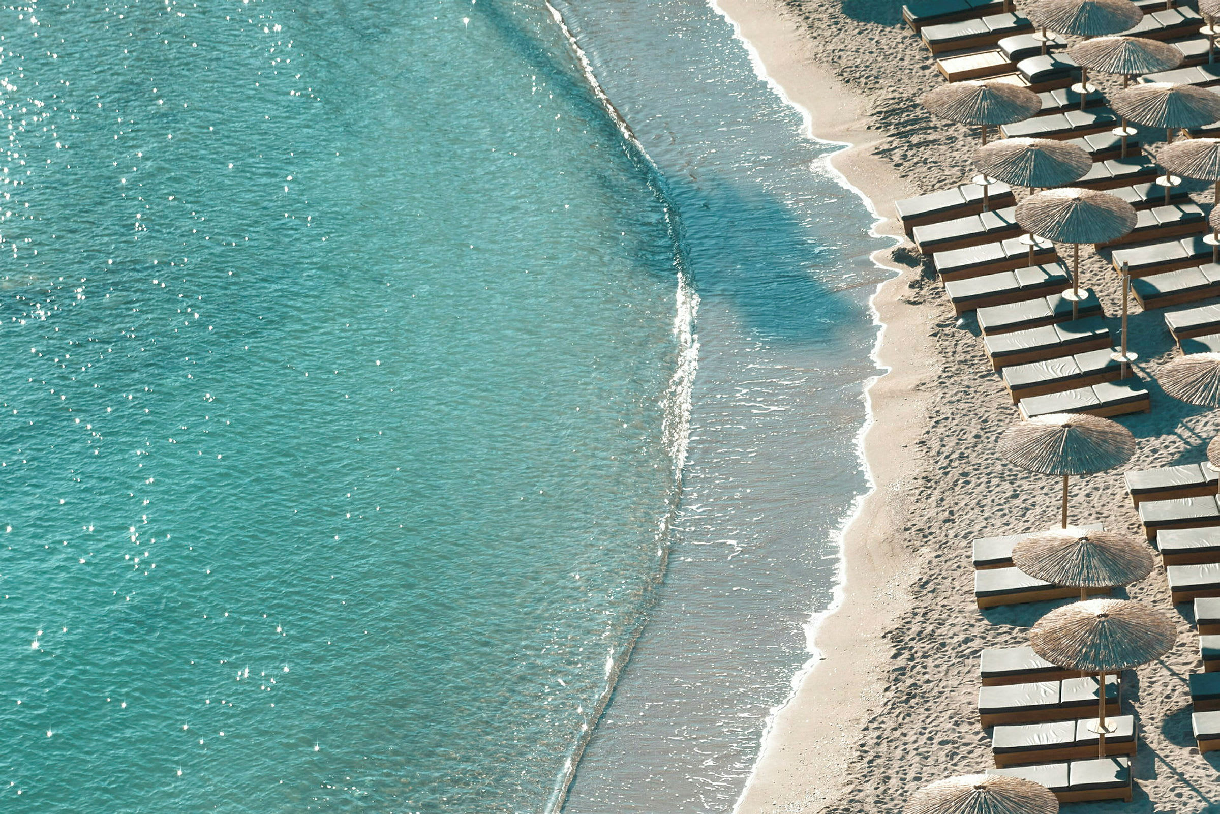 Strand med turkis vann og solsenger med parasoller. (AI-generert tekst)