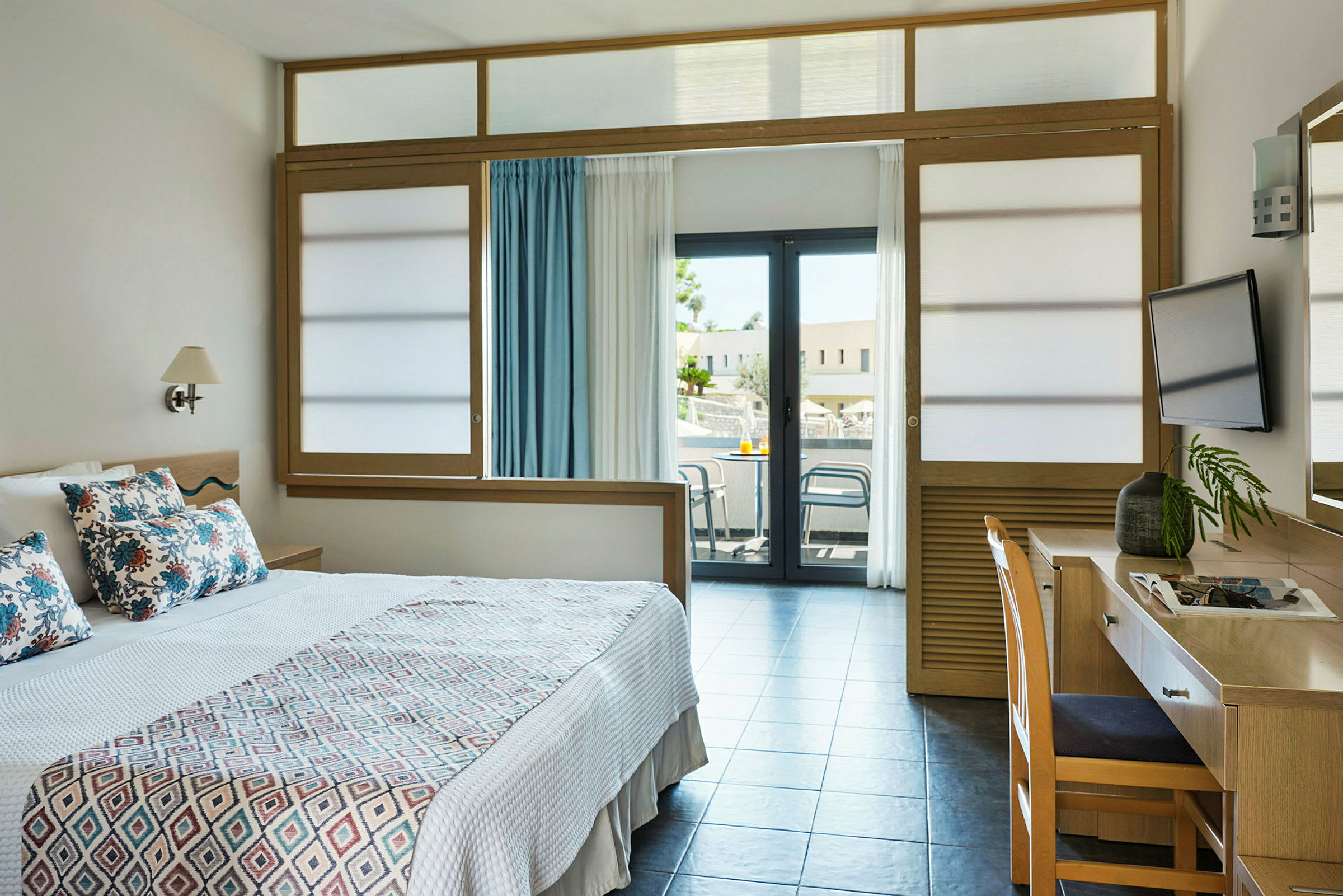 Hotellrom med en seng, skrivebord og balkong. (AI-generert tekst)