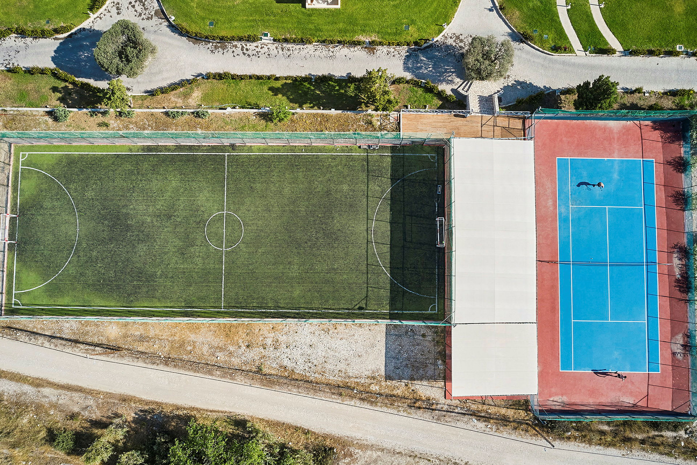 Flyfoto av en fotballbane og en tennisbane ved siden av hverandre. (AI-generert tekst)