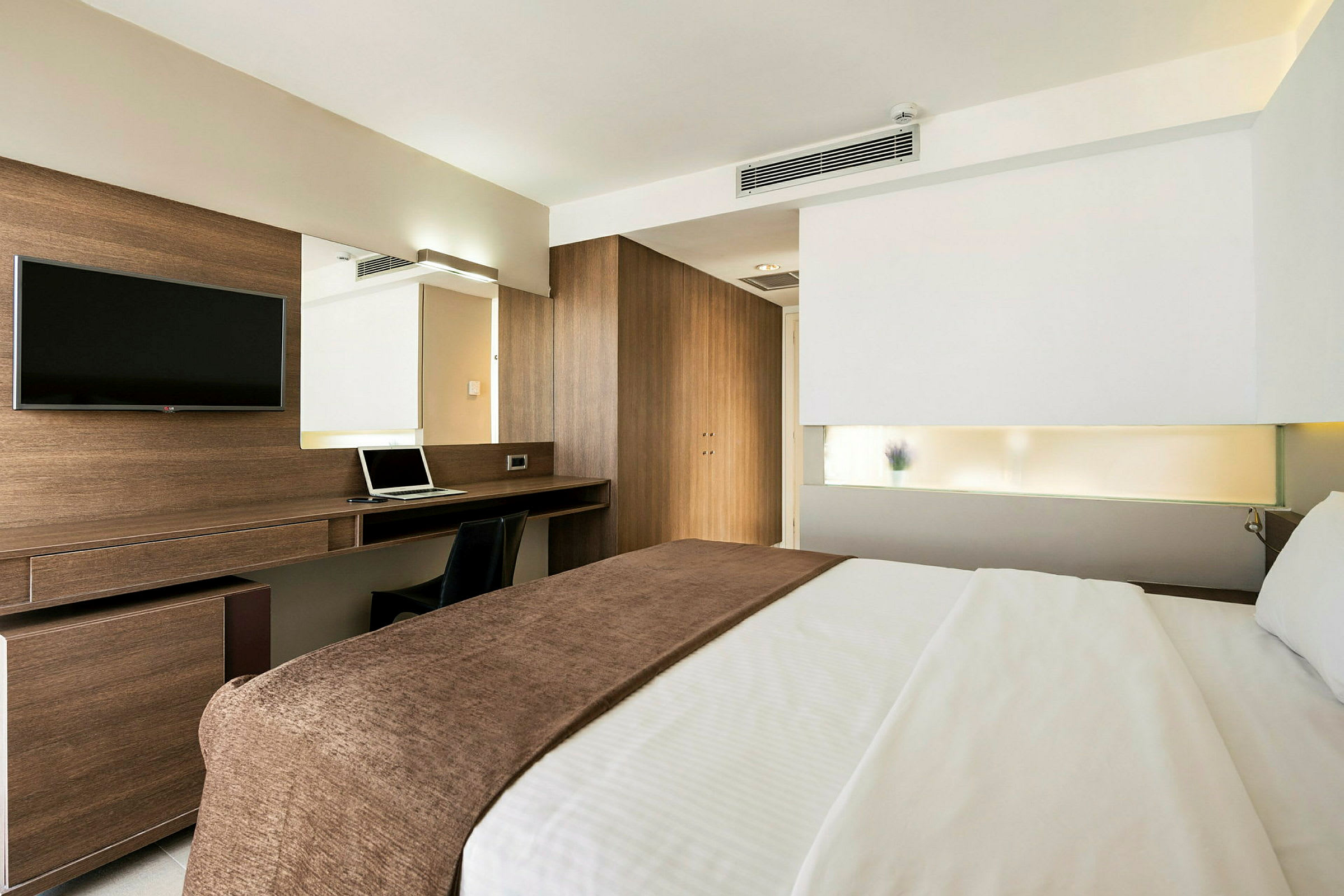 Et moderne hotellrom med en dobbeltseng, et skrivebord og en TV. (AI-generert tekst)