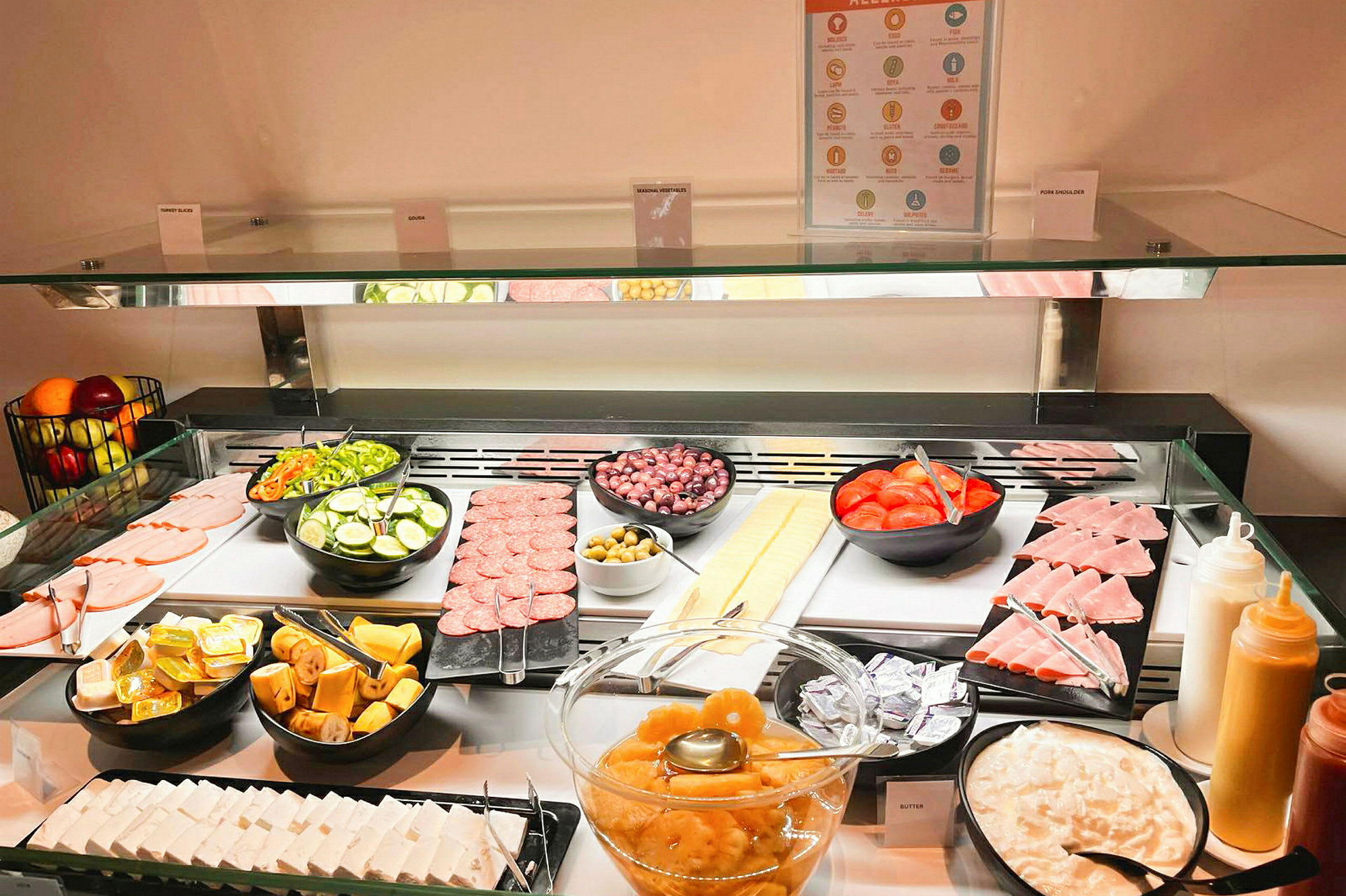 En buffet med skivede grønnsaker, kjøttprodukter, frukt og ulike tilbehør. (AI-generert tekst)