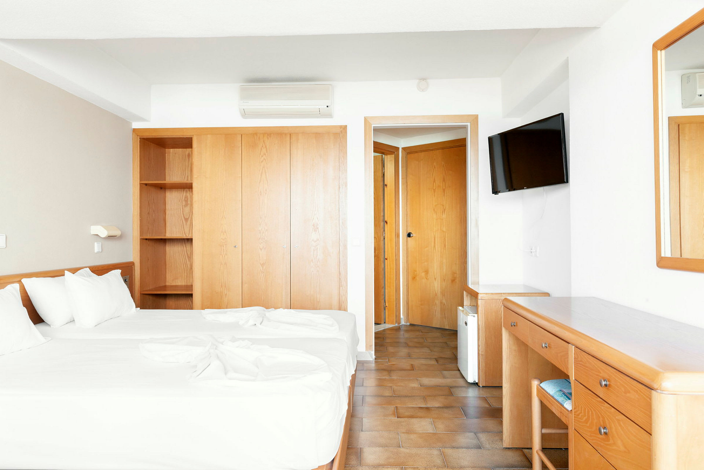 Hotellrom med to enkeltsenger, garderobe, skrivebord og speil. (AI-generert tekst)