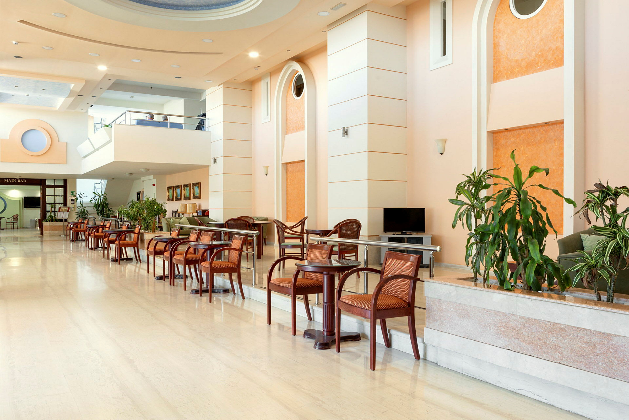 Et lyst hotellobbyområde med sitteplasser og planter. (AI-generert tekst)