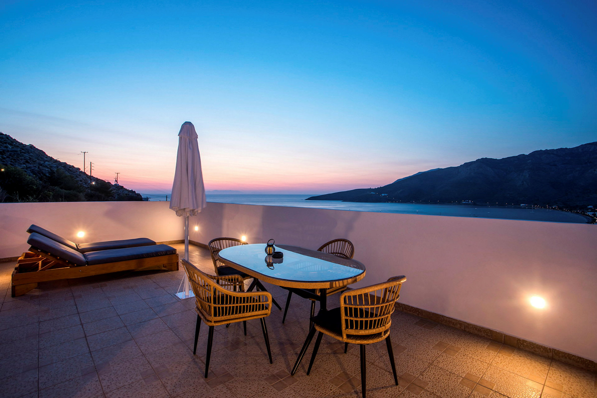 Terrasse med bord, stoler og solsenger ved solnedgang. (AI-generert tekst)