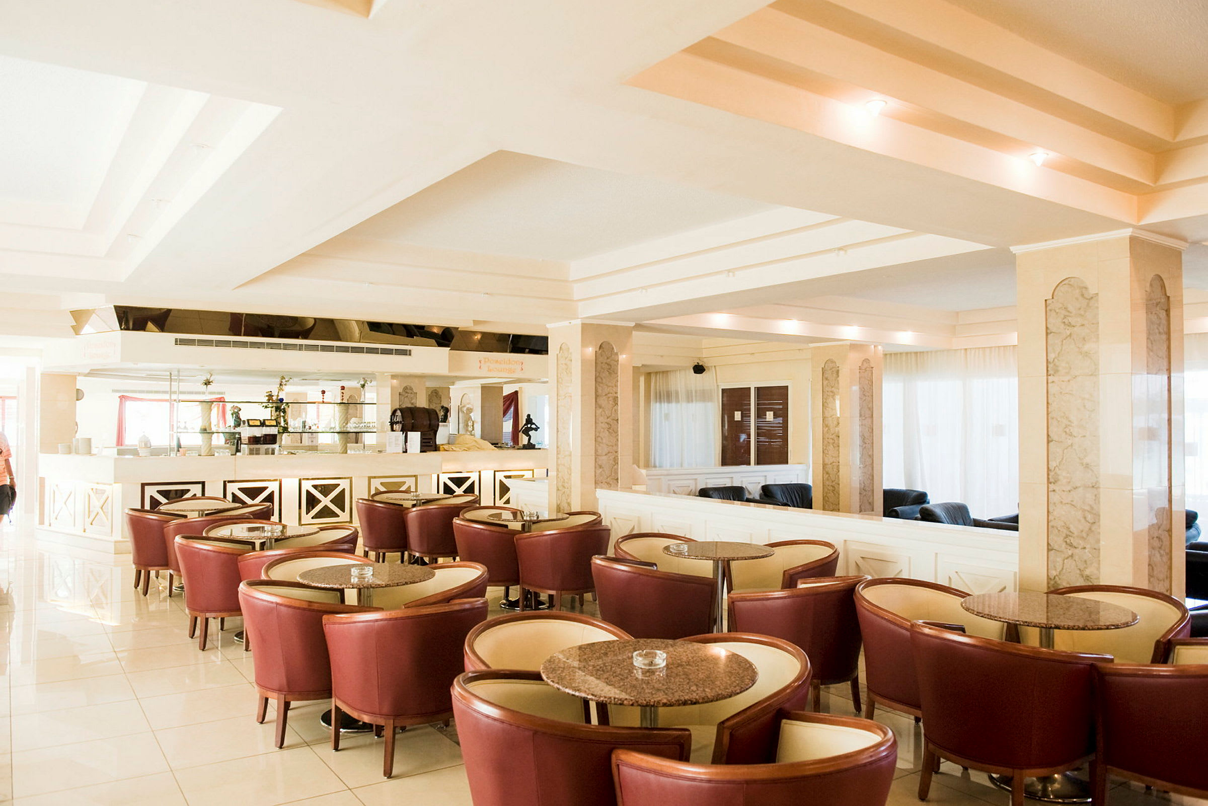 Bilde av en moderne hotellobby med røde stoler, runde bord og et godt opplyst interiør. (AI-generert tekst)